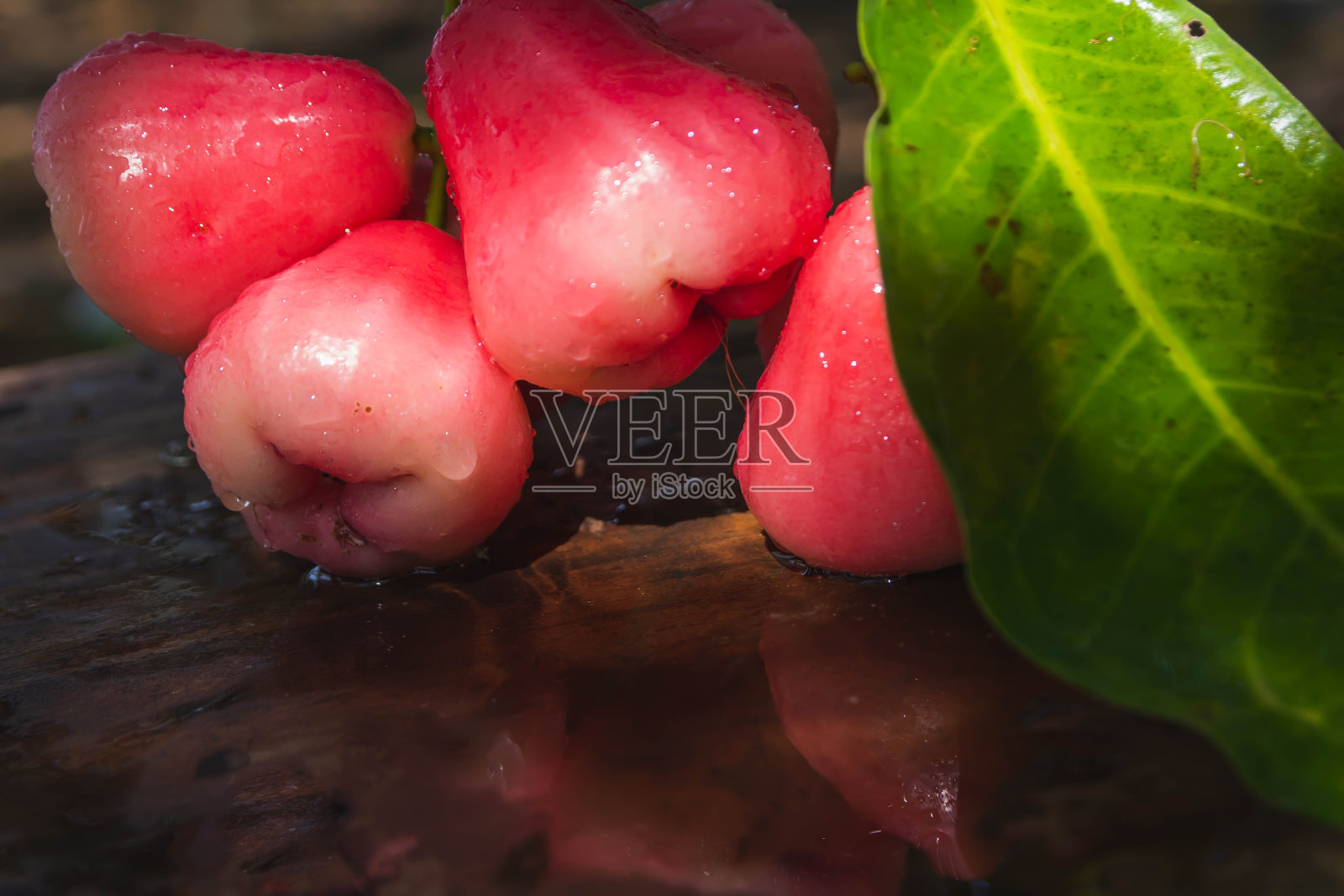 用清水清洗过并有水滴的红玫瑰苹果，放在木桌上照片摄影图片
