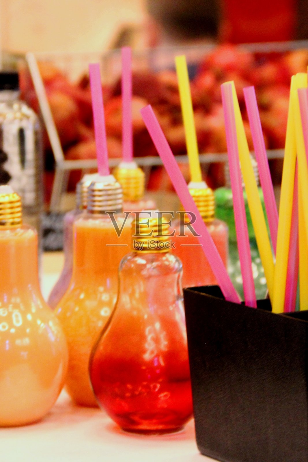 许多灯泡形状的小瓶子，装满了鲜艳的颜色有用的水果和蔬菜汁和饮用吸管在食品广场的柜台上，特写照片摄影图片