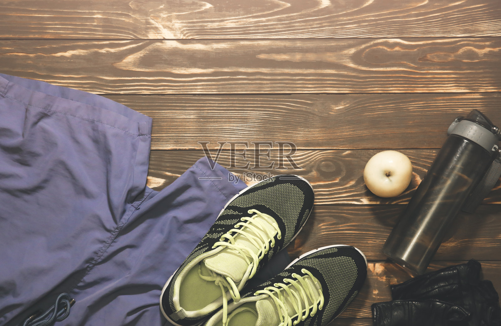 健康概念的照片。运动鞋，一瓶水，短裤和皮手套。水果和苹果躺在木制的背景上。健康的生活方式。运动动机的背景。照片摄影图片