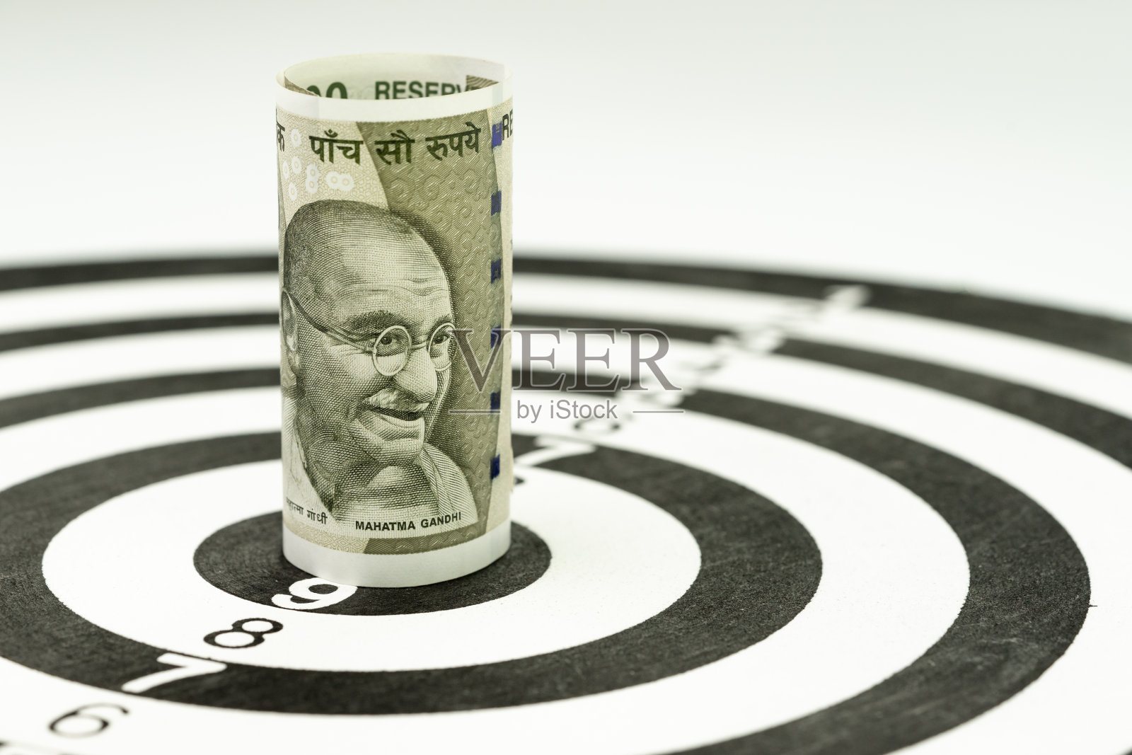 财务目标或目标概念，印度卢比纸币的滚动目标对准黄色的圆靶的中心照片摄影图片