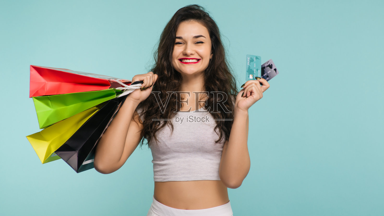 快乐的女人，黄色背景上有五颜六色的包装，在购物照片摄影图片