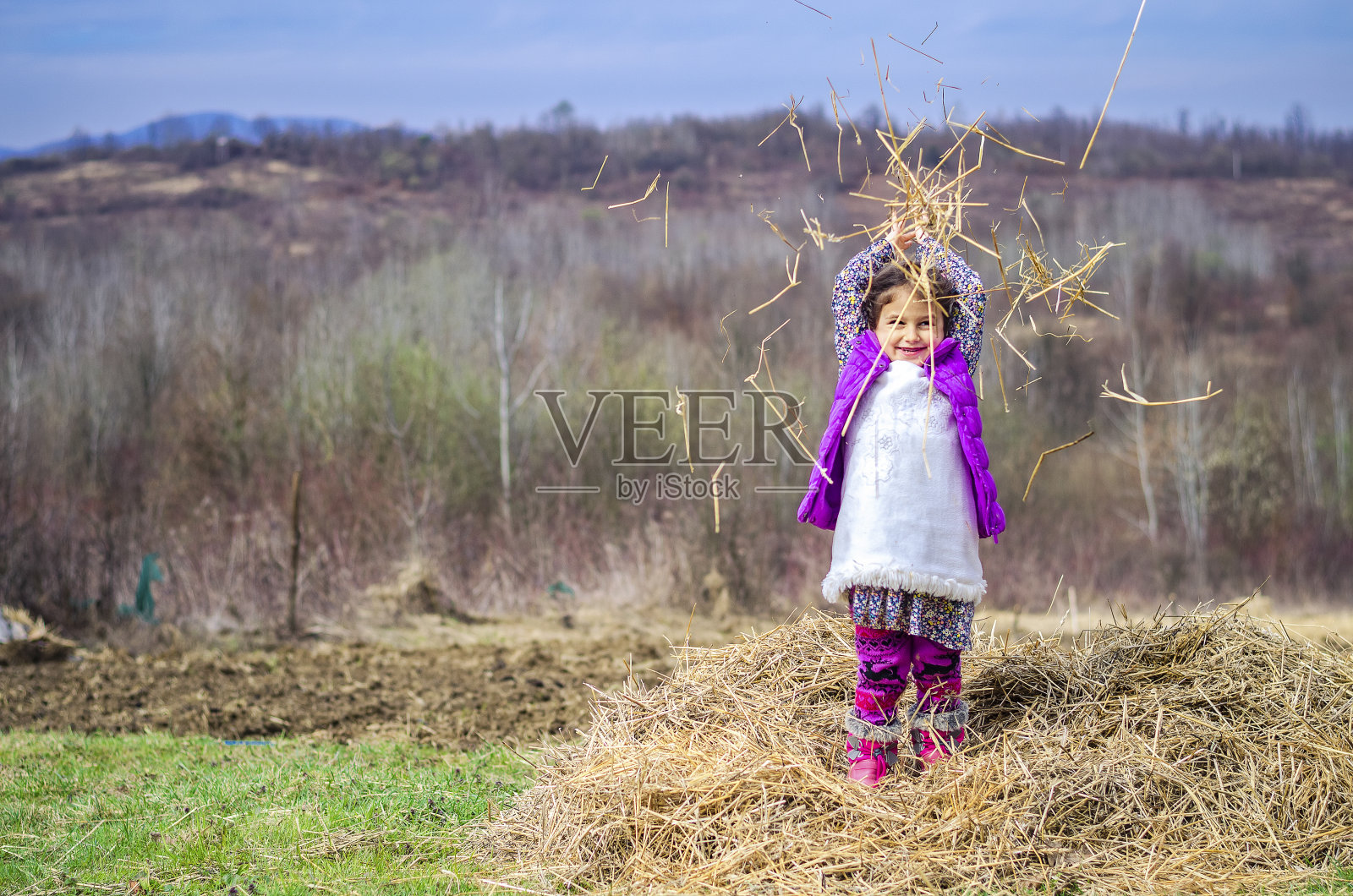快乐的乡下小女孩在地里玩着干稻草照片摄影图片