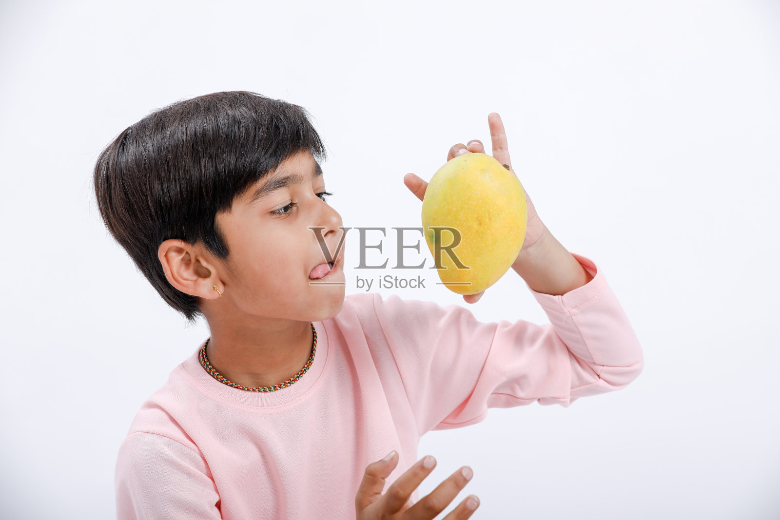 可爱的印度/亚洲小男孩吃芒果，表情多样。在白色背景上隔离照片摄影图片