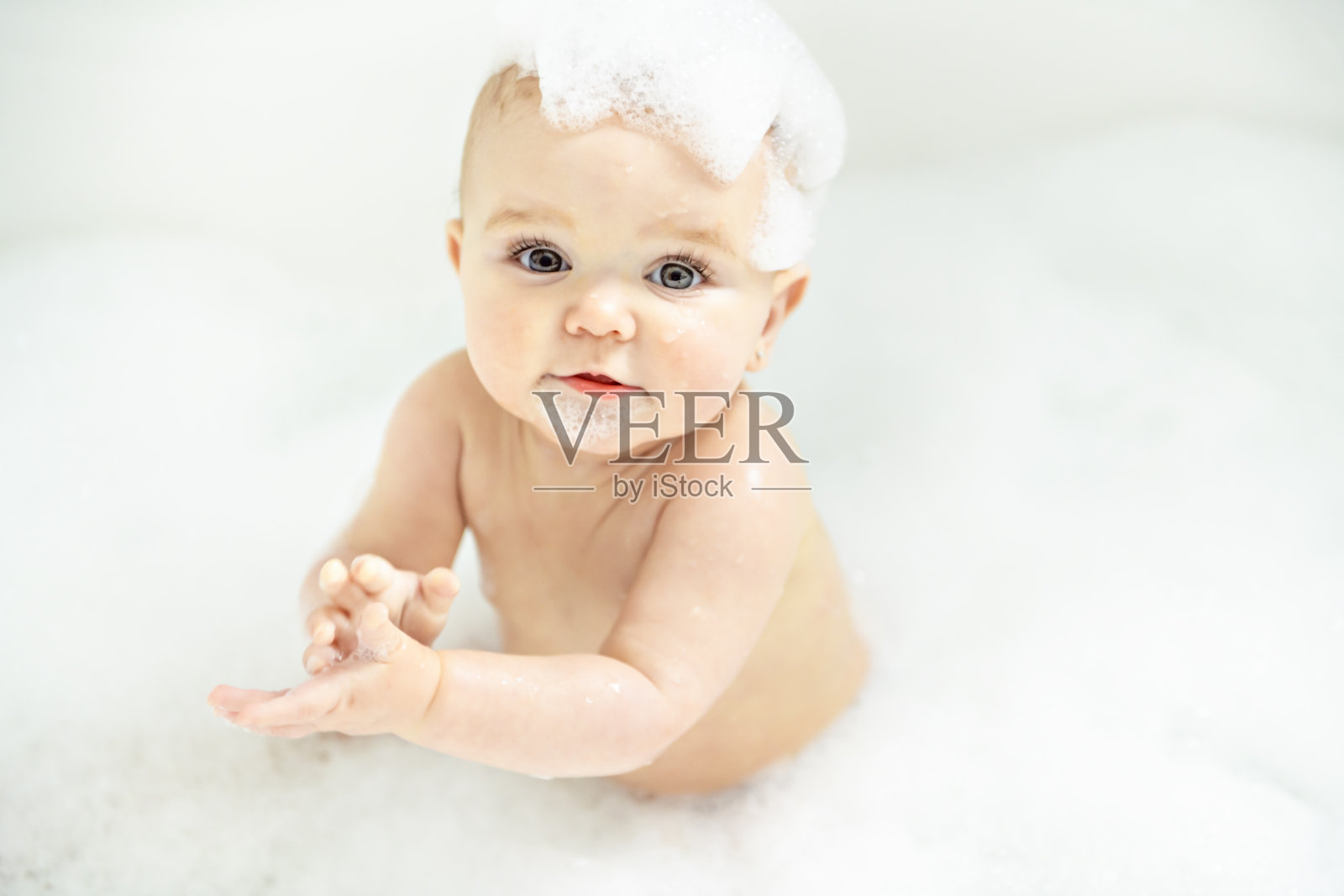 一个女婴在充满泡沫和肥皂泡的浴缸中沐浴照片摄影图片