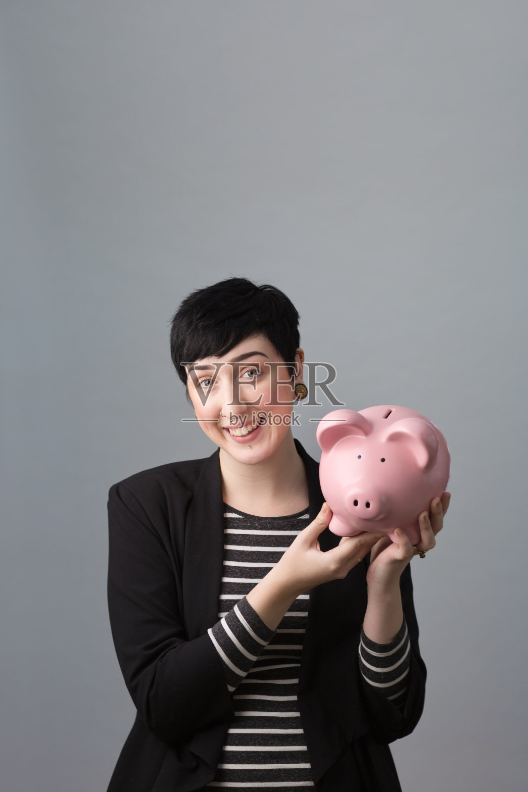 千禧一代年轻女性的肖像与小猪储蓄银行的财务管理照片摄影图片