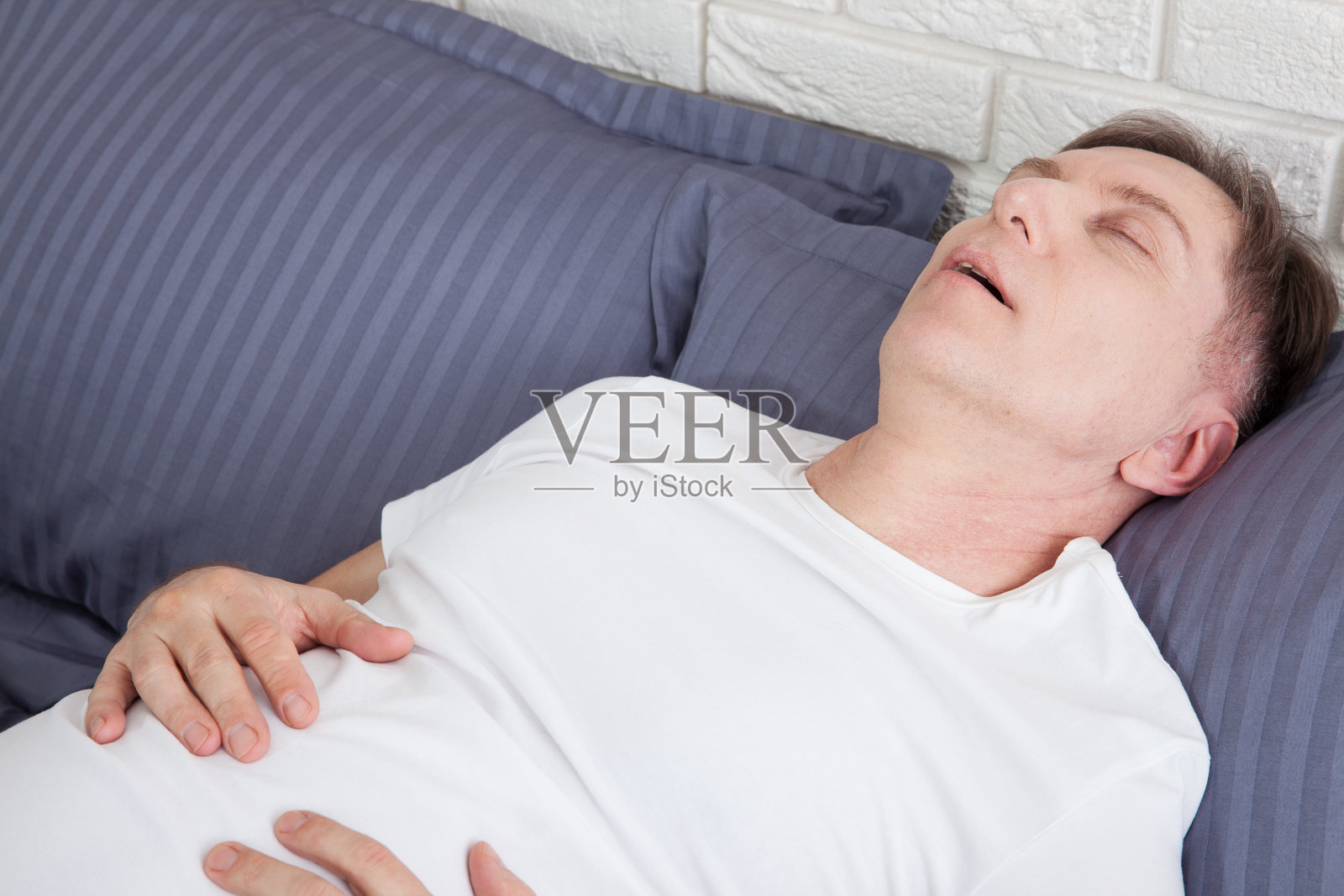 男人因为睡眠呼吸暂停而打鼾躺在床上照片摄影图片