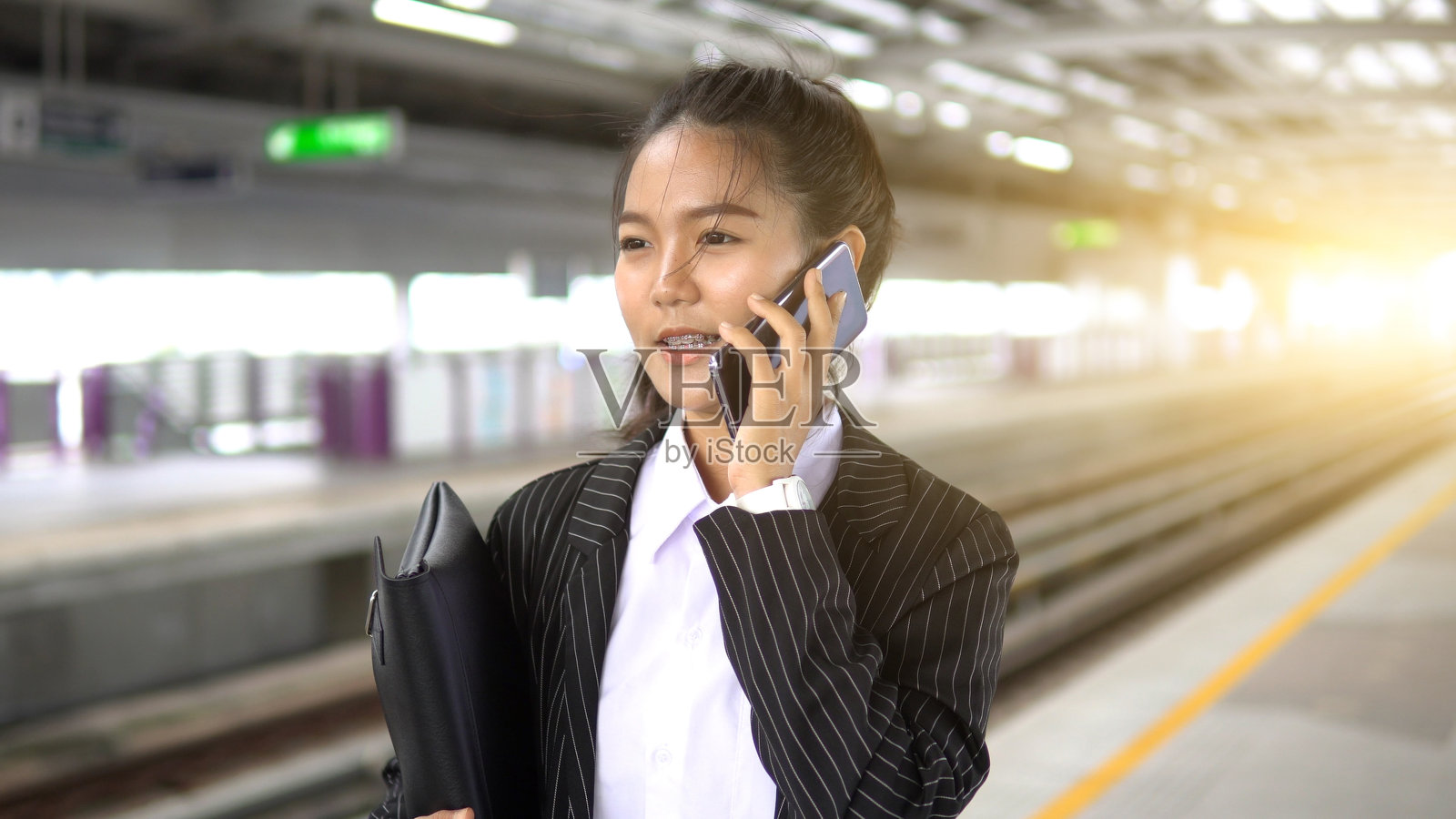 亚洲女性乘客穿着休闲服装，在轻轨或地铁上看钟和打电话，以在大城市旅行，生活方式和交通理念照片摄影图片