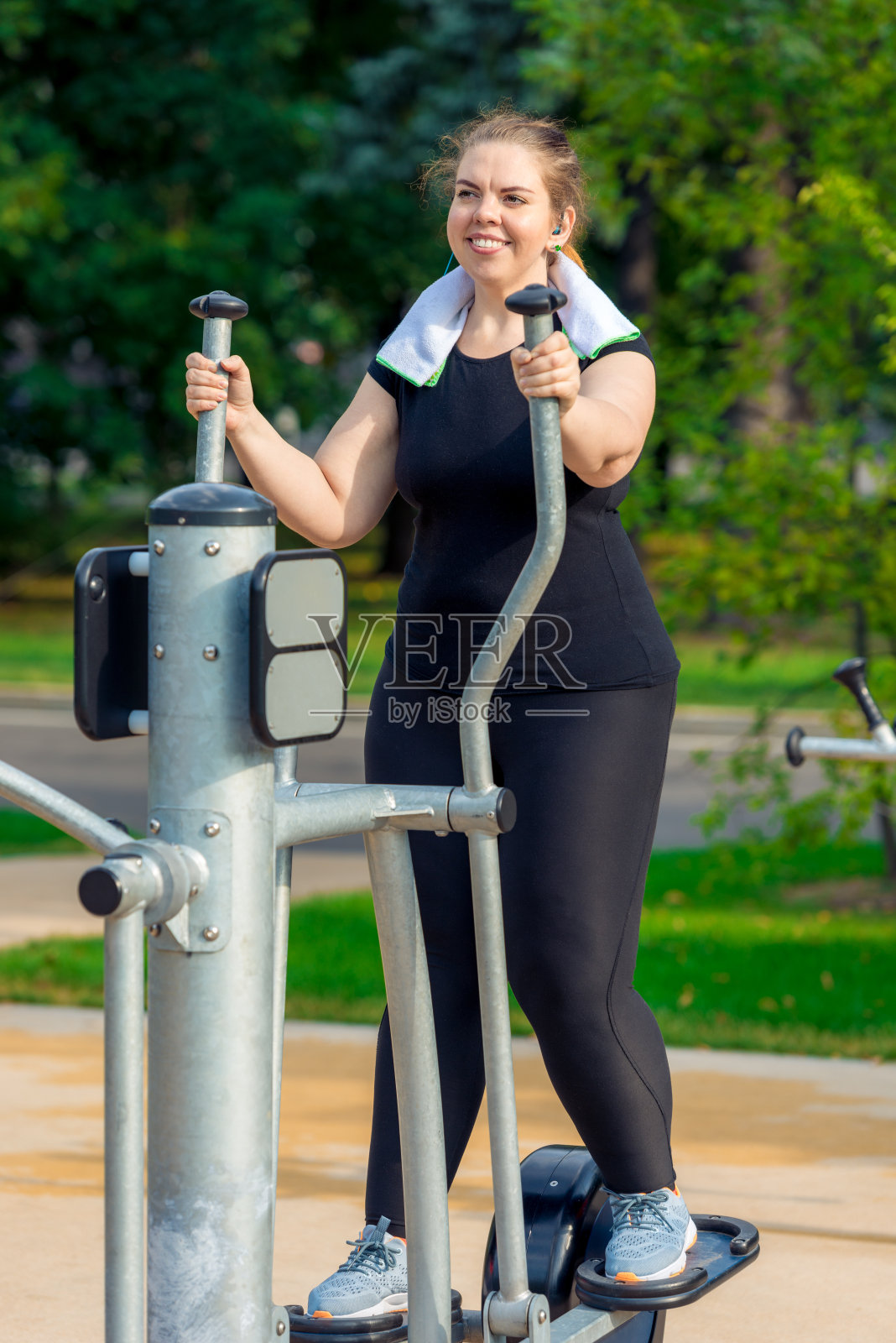 一个活跃的胖女人的肖像没有复杂的是从事在公园的步模拟器照片摄影图片