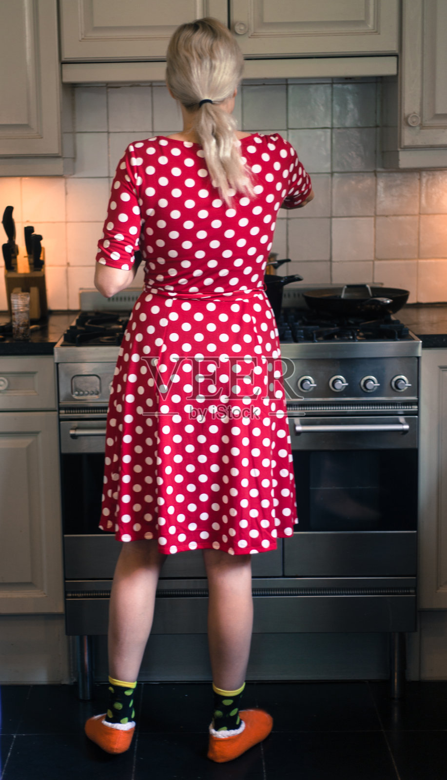 穿着圆点裙的年轻女子在炉子上做饭照片摄影图片