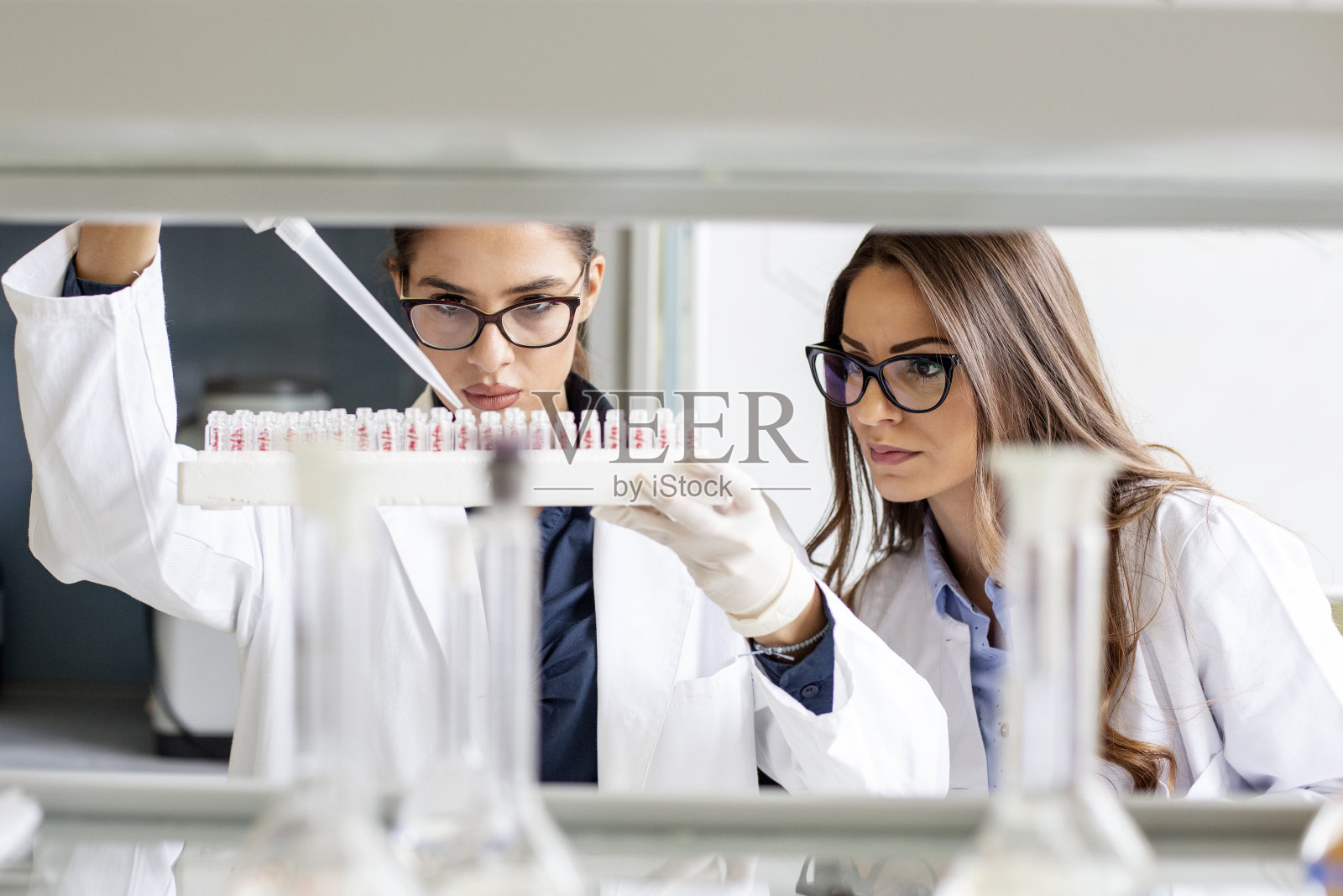 在实验室里，两个年轻女子在做一些试验照片摄影图片