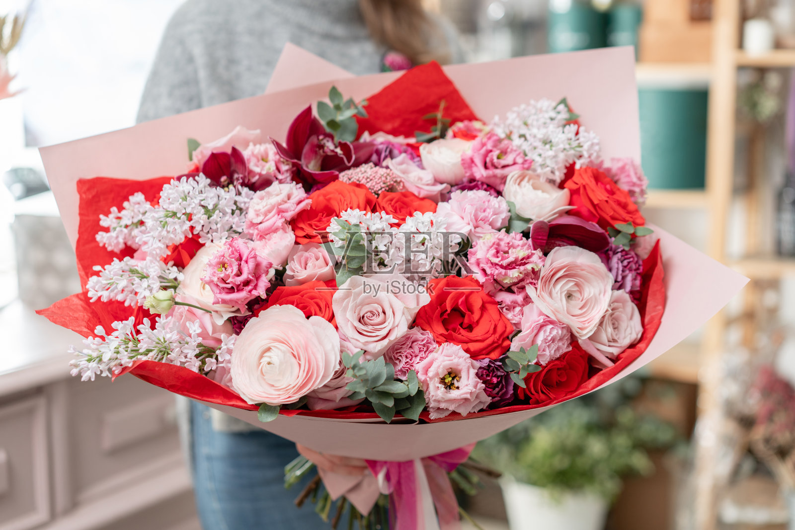 美丽的新鲜切花束混合在女人的手。花店花匠的工作。红色和粉红色照片摄影图片
