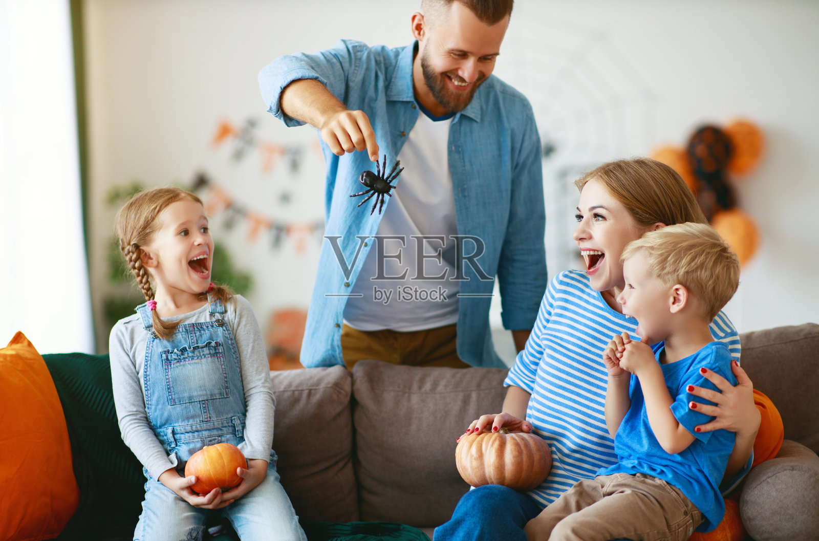 快乐的家庭妈妈爸爸和孩子们准备万圣节用南瓜装饰家和欢笑，玩和蜘蛛惊吓照片摄影图片