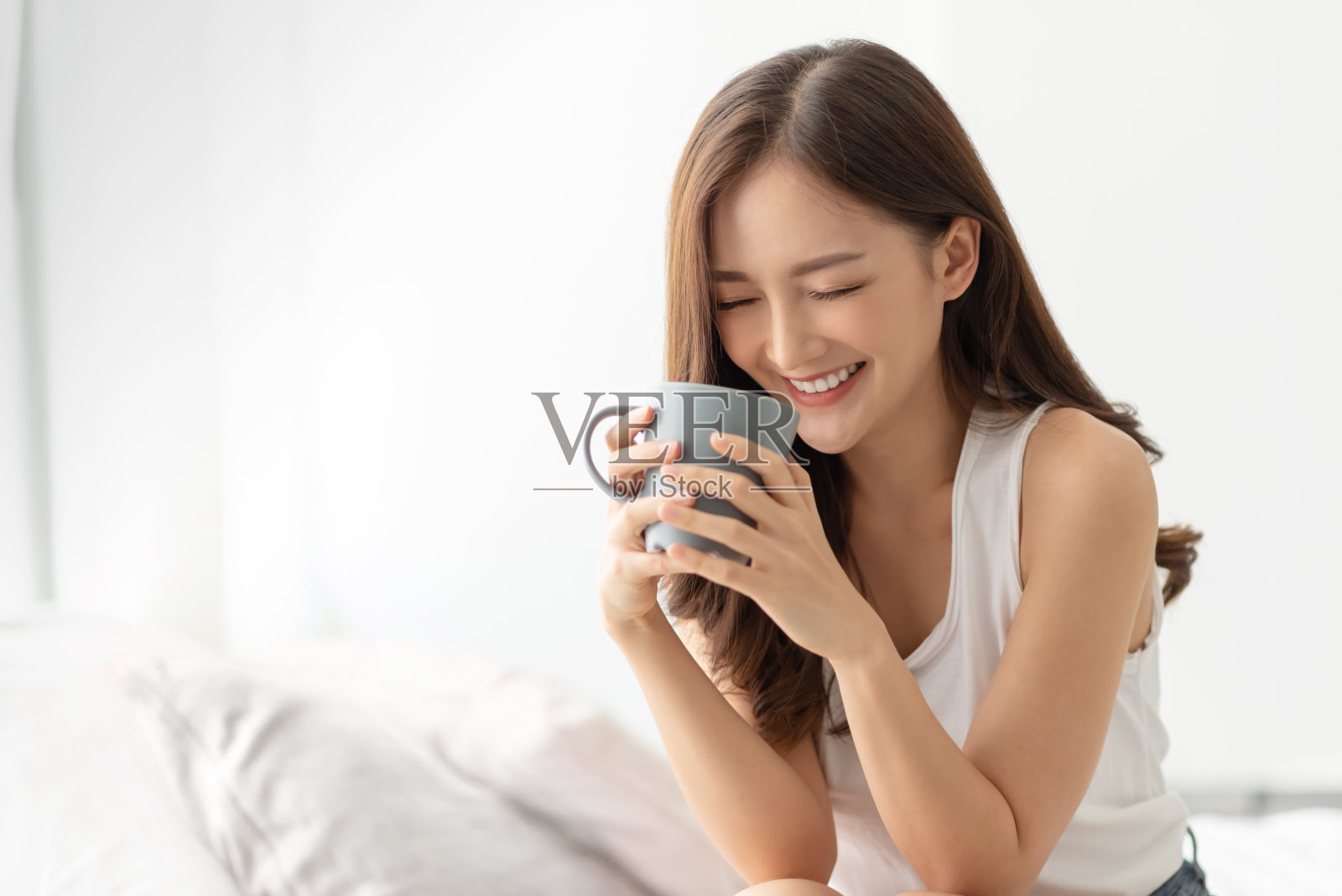 快乐年轻的亚洲女人是放松与一杯热饮料。照片摄影图片