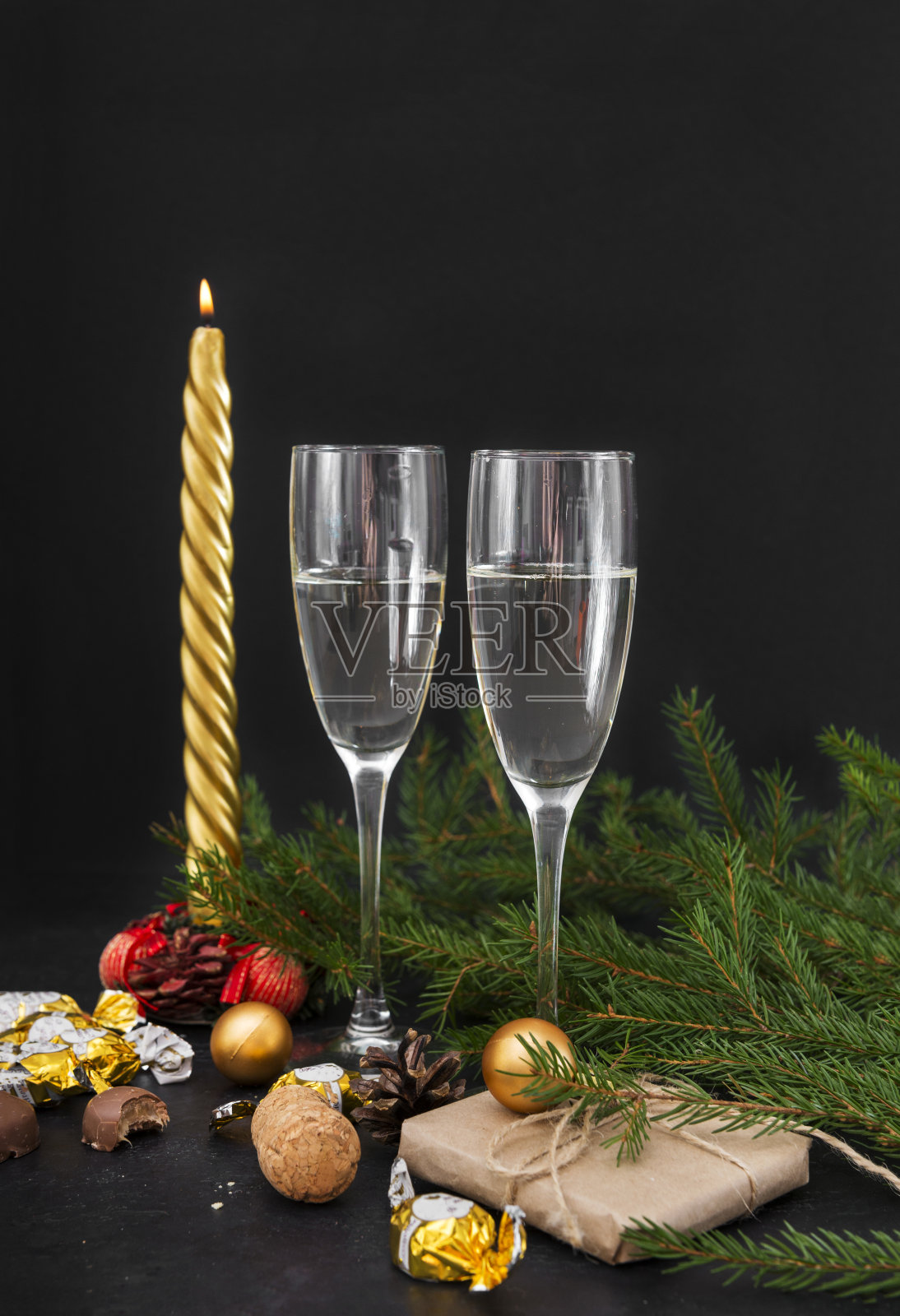 云杉树枝，两杯香槟，用金色包装纸包装的巧克力，礼品盒，蜡烛，气球，汽酒，圣诞装饰品照片摄影图片