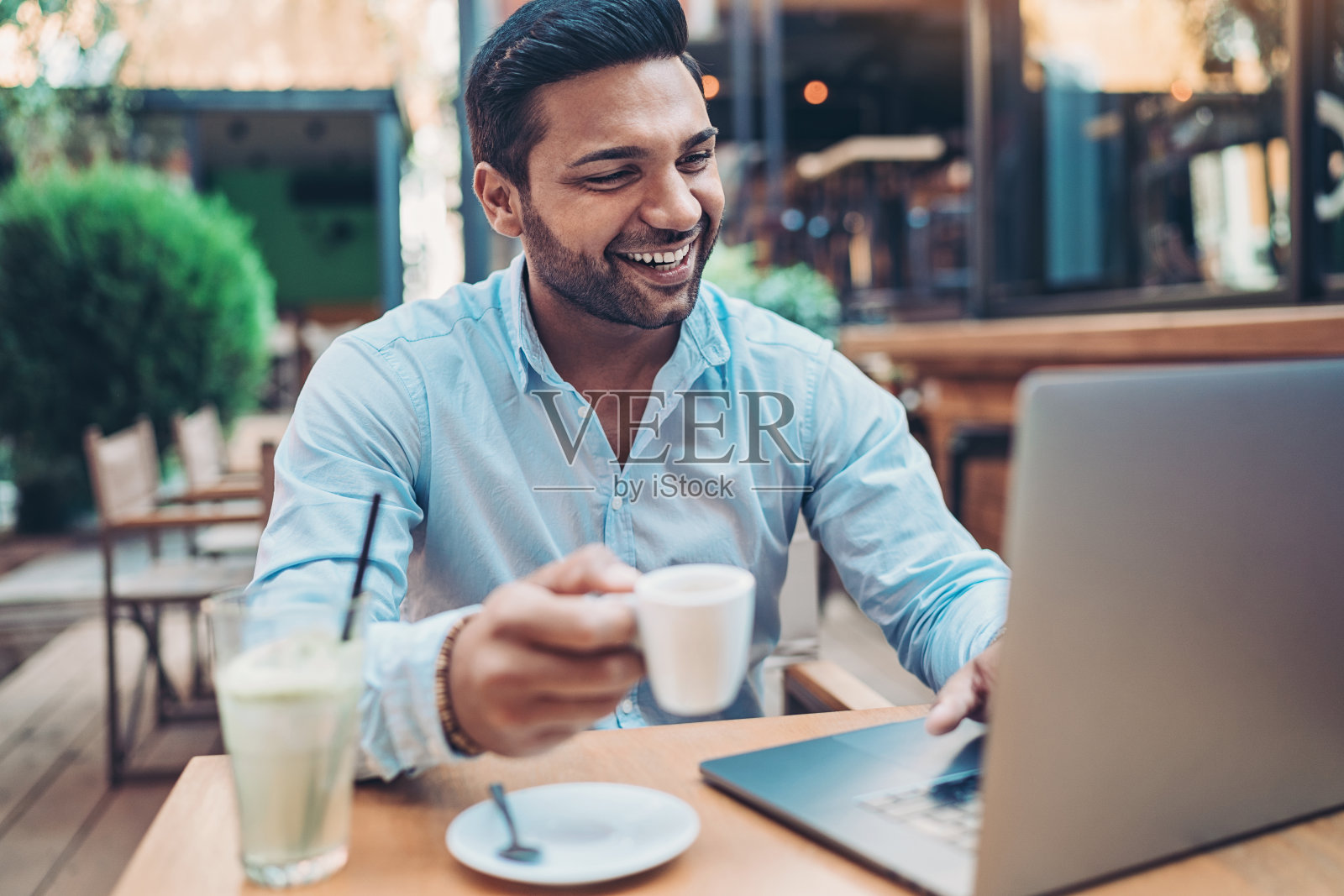 微笑的男人在自助餐厅使用笔记本电脑照片摄影图片