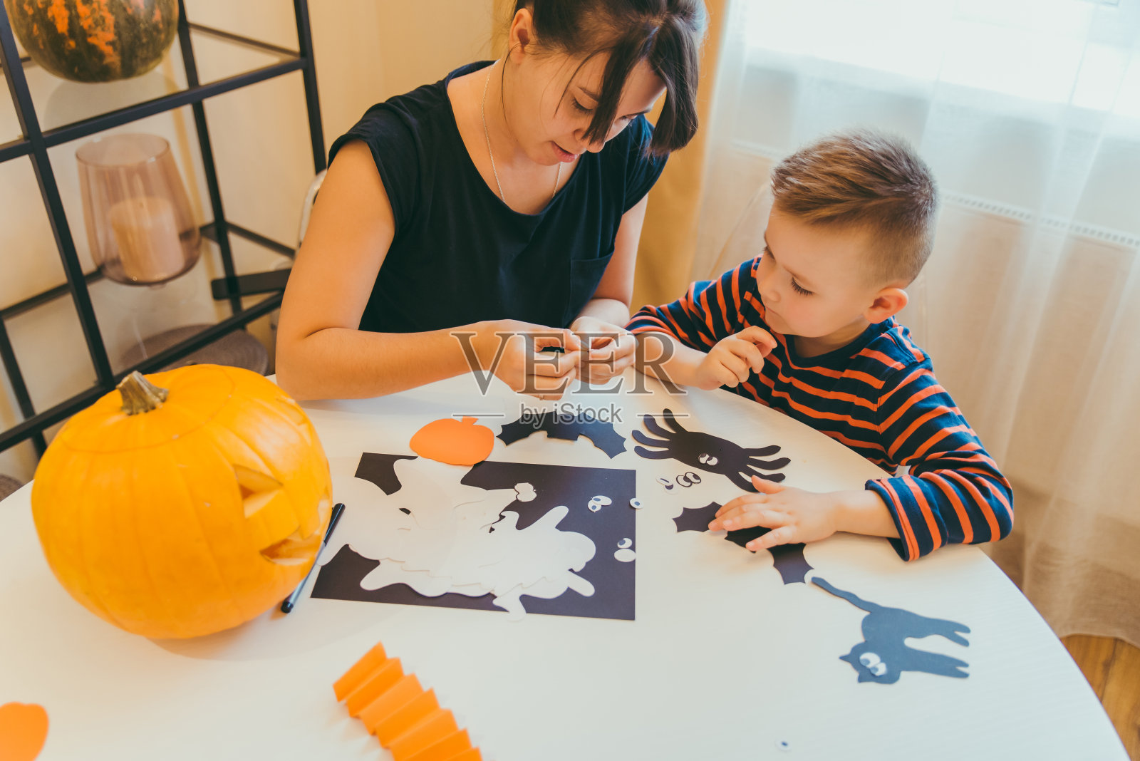 年轻的母亲和蹒跚学步的儿子制作工艺蜘蛛万圣节假期家庭时间照片摄影图片