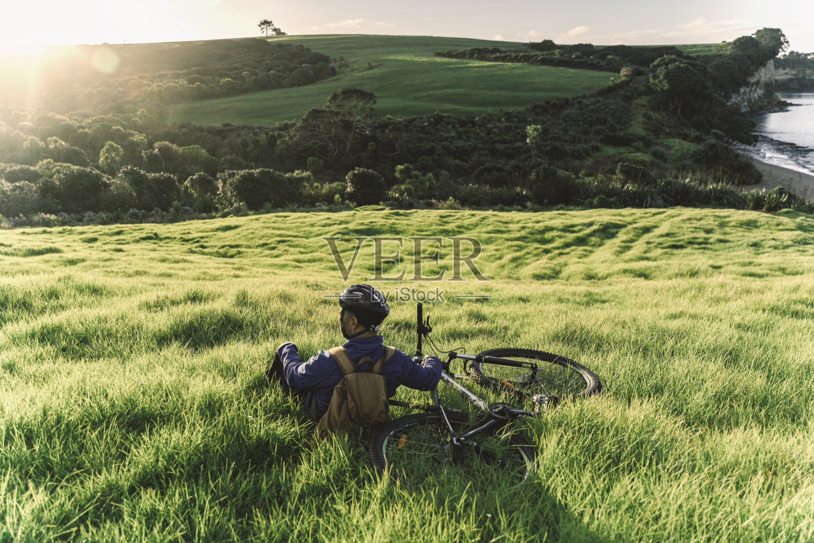 专业的公路自行车手坐在开阔的田野上观看日落照片摄影图片