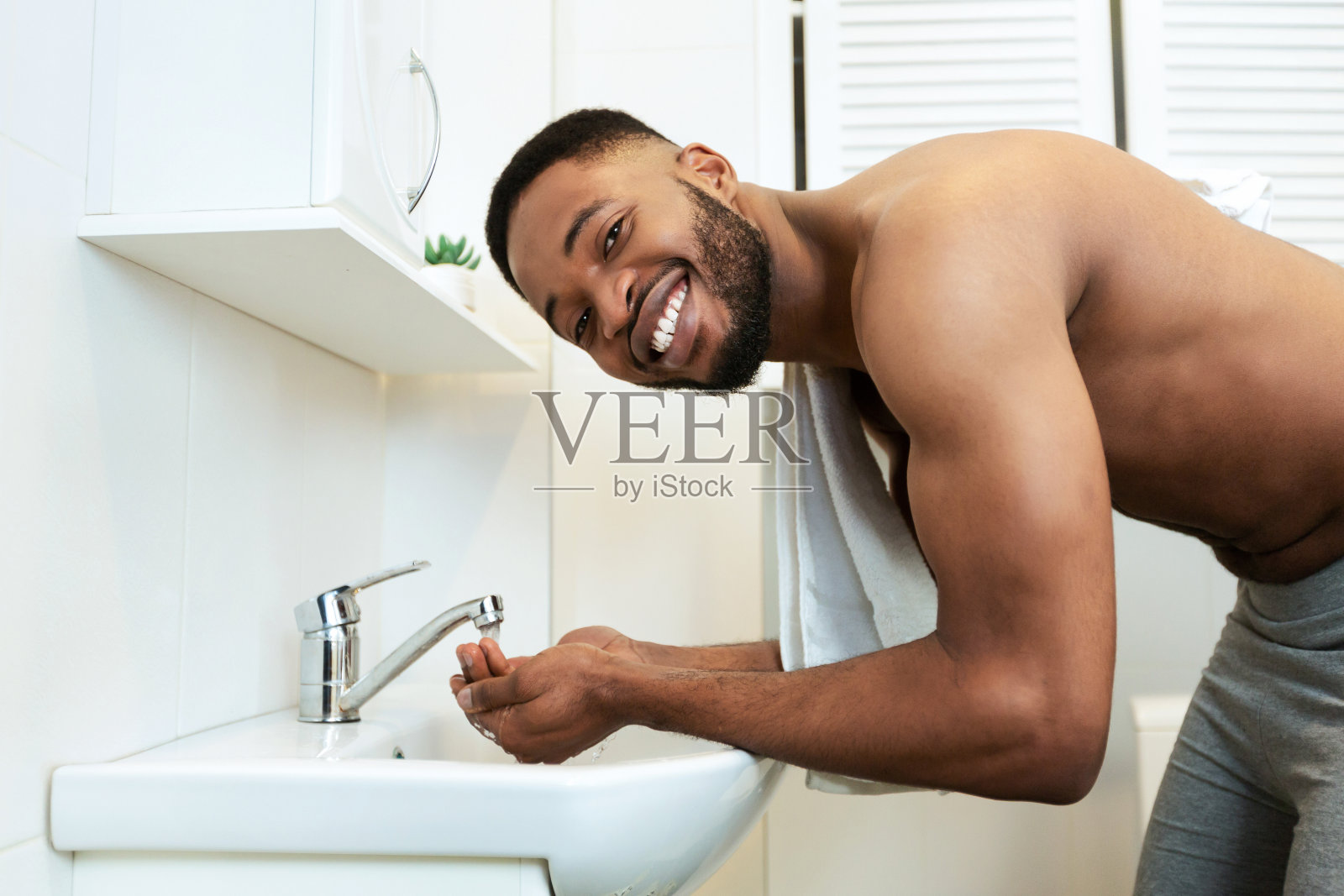 赤裸上身的非洲千禧一代在浴室里洗脸照片摄影图片