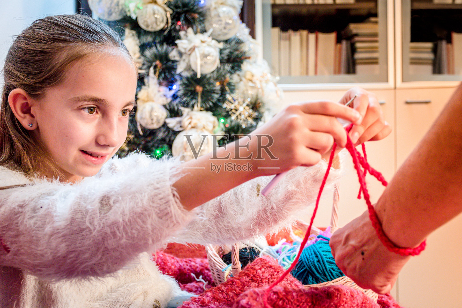 微笑的女孩编织手镯给奶奶在圣诞节时间照片摄影图片