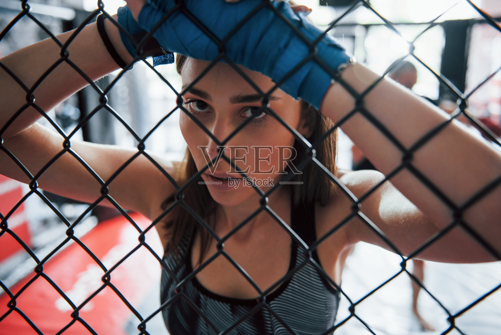 休息。女运动员在拳击台上锻炼身体。靠在篱笆上照片摄影图片