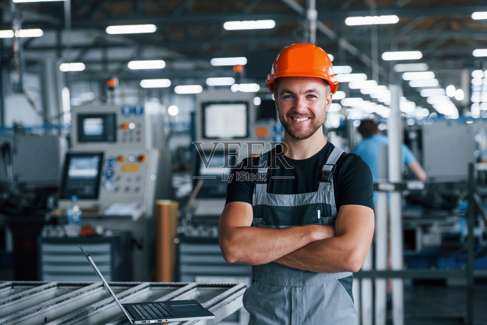 微笑和快乐的员工。工厂内的工业工人。戴着橙色安全帽的年轻技术员照片摄影图片