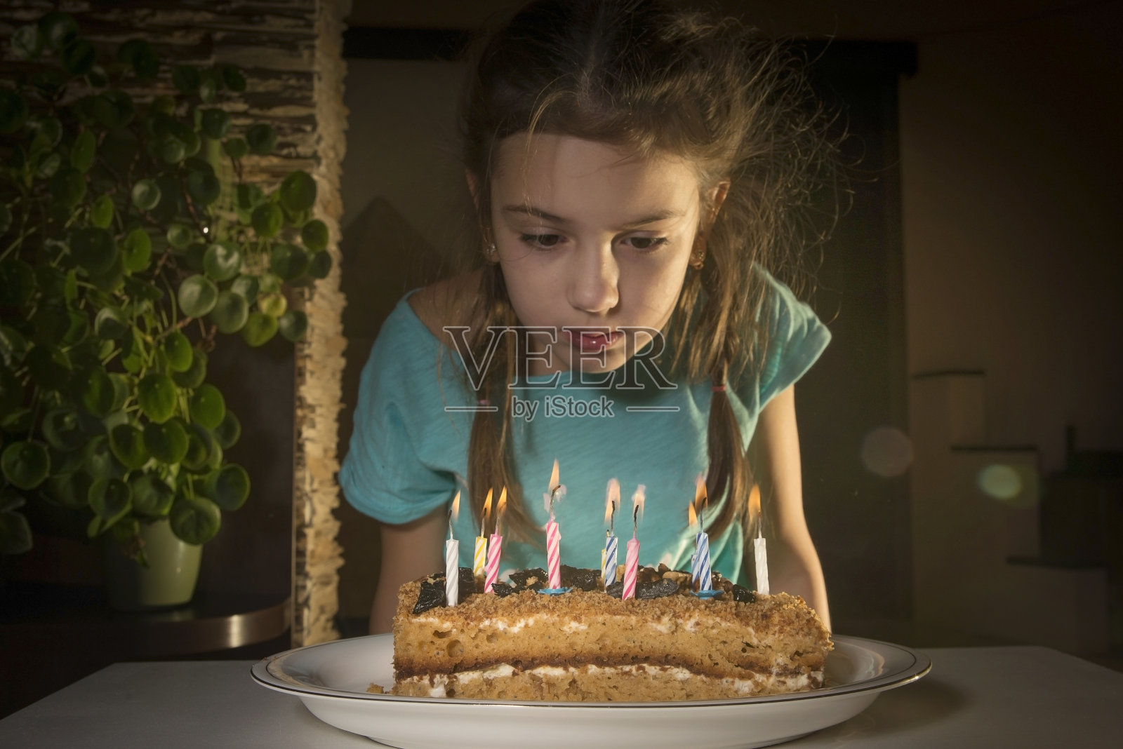 一个女孩吹灭生日蛋糕上的蜡烛。照片摄影图片