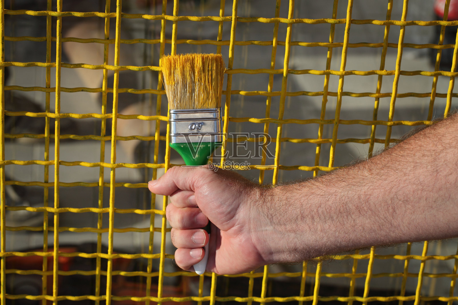 工人将金属防护网涂成黄色照片摄影图片