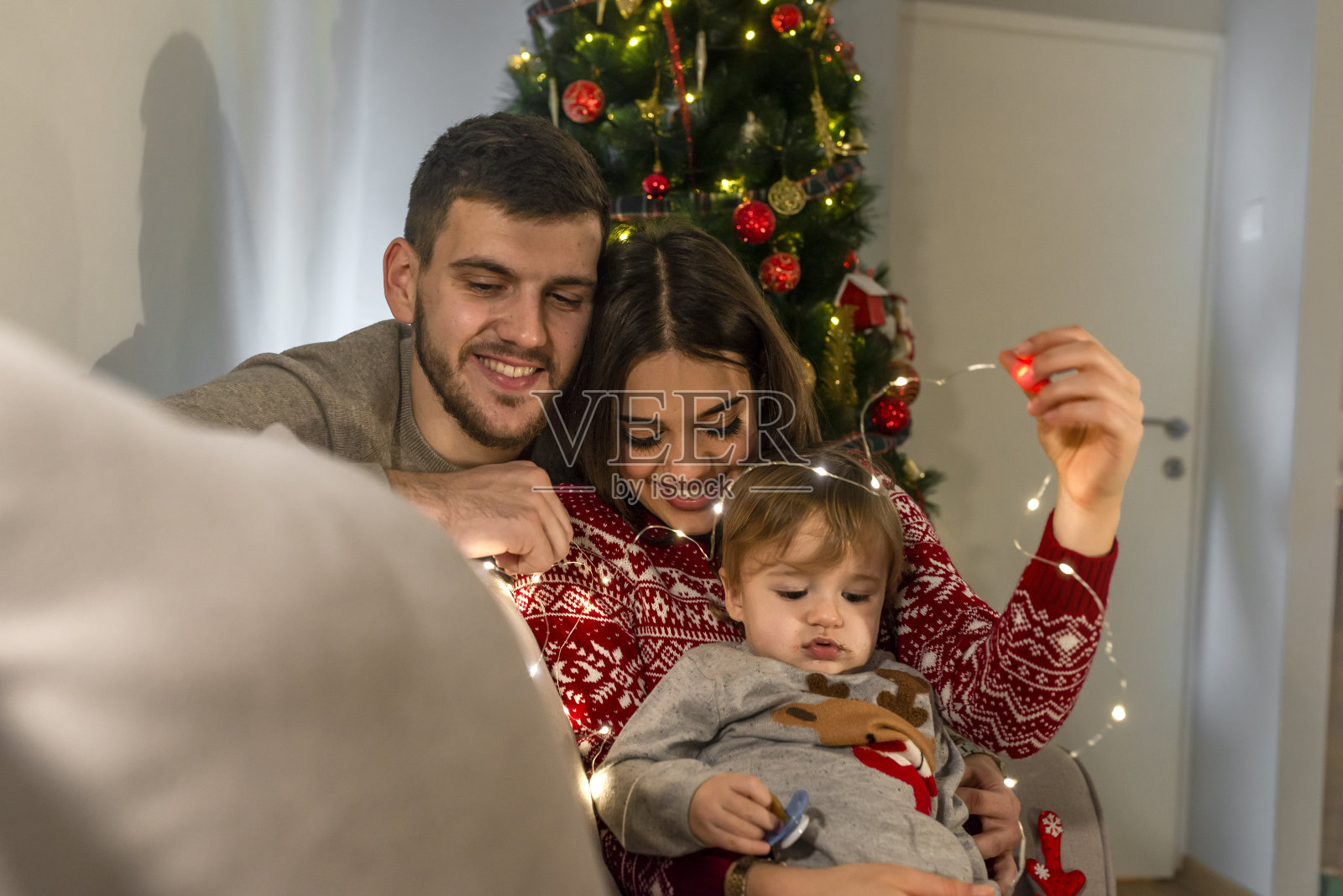年轻的家庭和儿子在圣诞树在家里照片摄影图片
