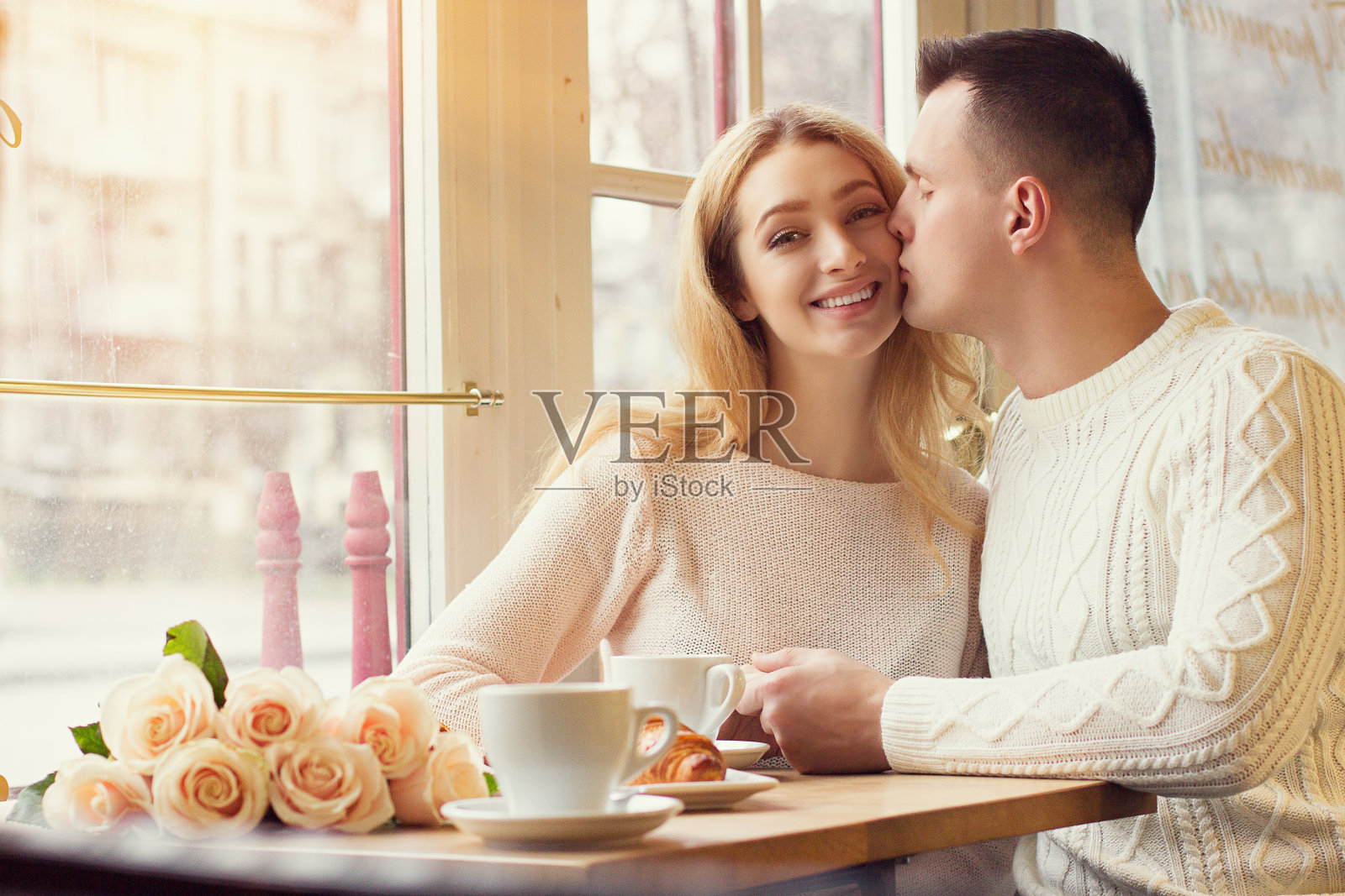 一个男人在舒适的咖啡馆里亲吻他微笑的女朋友照片摄影图片