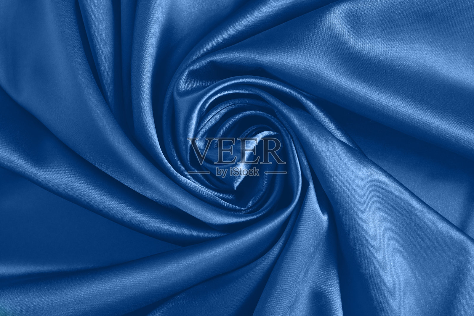 蓝色丝绸织物上玫瑰花瓣形状的波纹的特写。缎织物背景。照片摄影图片