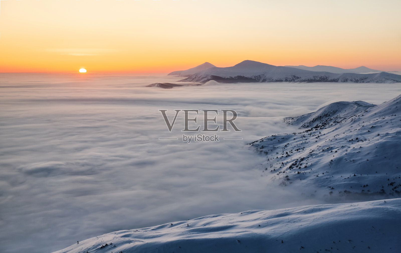 风景有高山，晨雾和美丽的日出。橙色的天空。冬天的风景。壁纸背景。地点:欧洲，乌克兰，喀尔巴阡。照片摄影图片