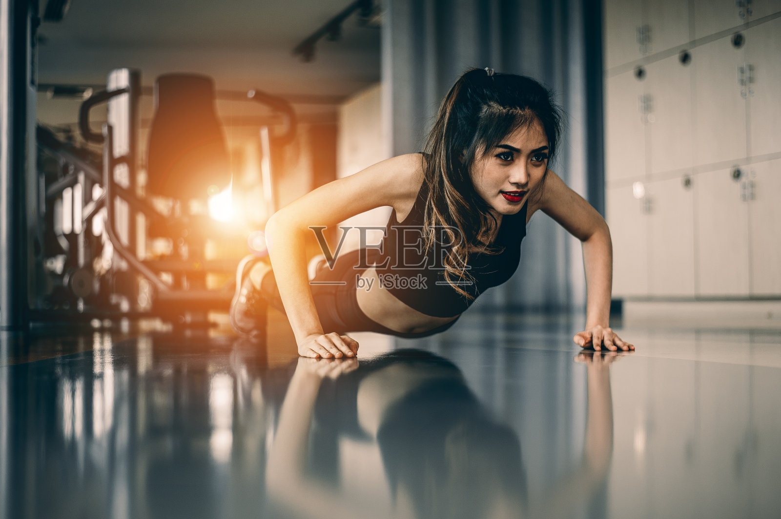 一个年轻女子在健身房做俯卧撑。照片摄影图片