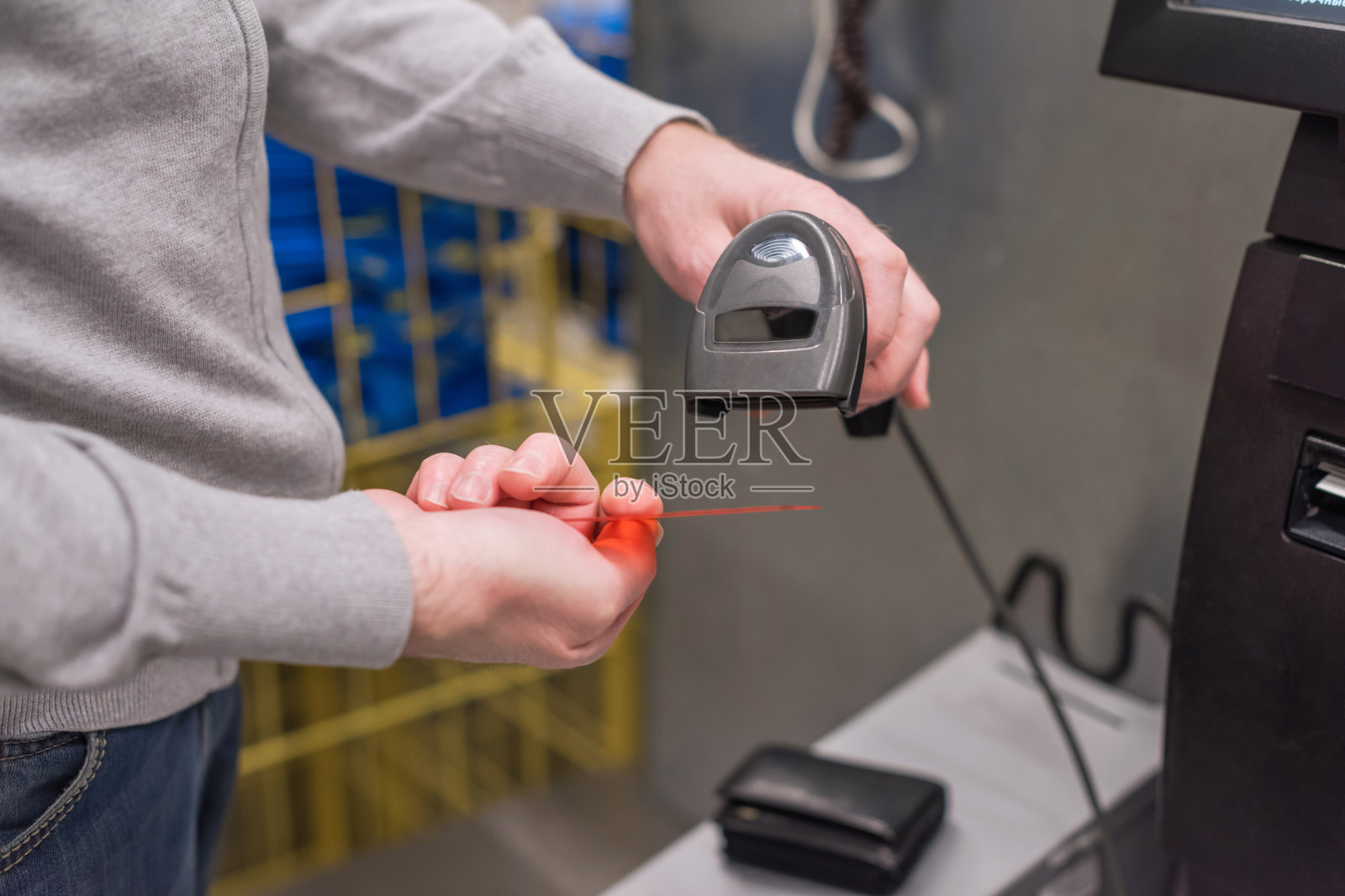 一名男子在自助服务柜台付款，并在刷卡机上输入信用卡密码以获取安全密码。购物时间照片摄影图片