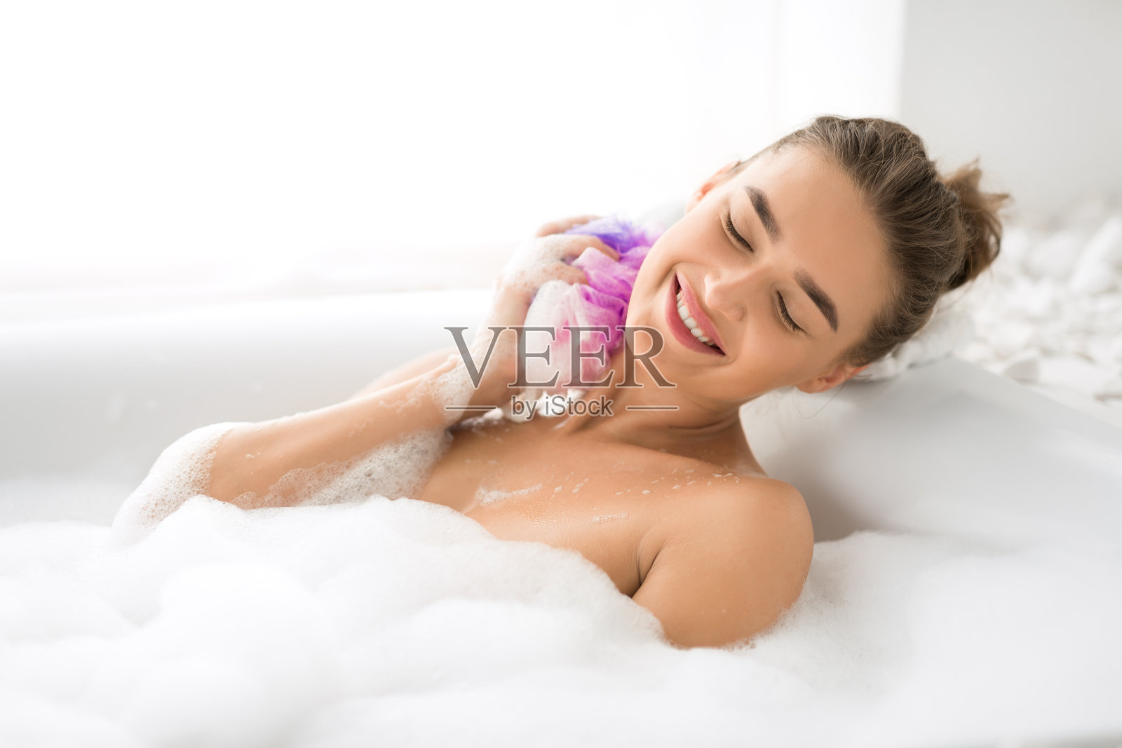 快乐的女人用海绵洗澡，放松的沐浴照片摄影图片