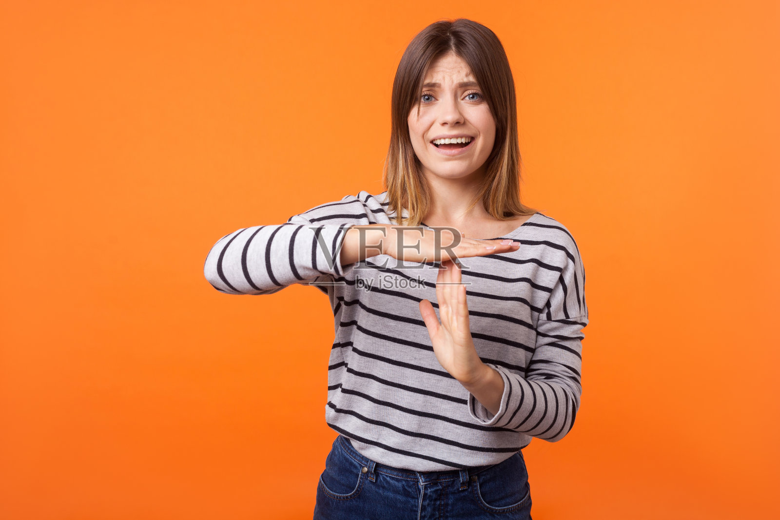 请时间!肖像担心不安的年轻女子棕色头发在长袖条纹衬衫。室内工作室拍摄孤立的橙色背景照片摄影图片