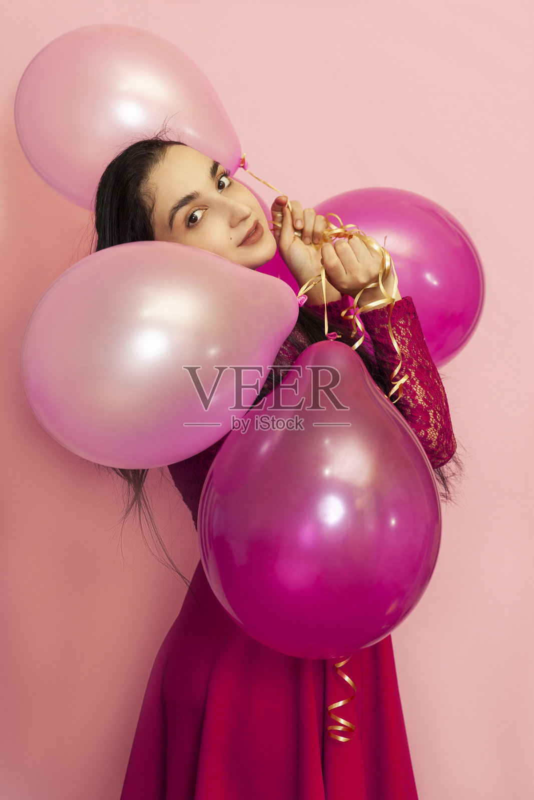 年轻漂亮的女人穿着红色晚礼服拿着节日的气球。肖像快乐的20岁中东女性庆祝情人节，生日，派对照片摄影图片