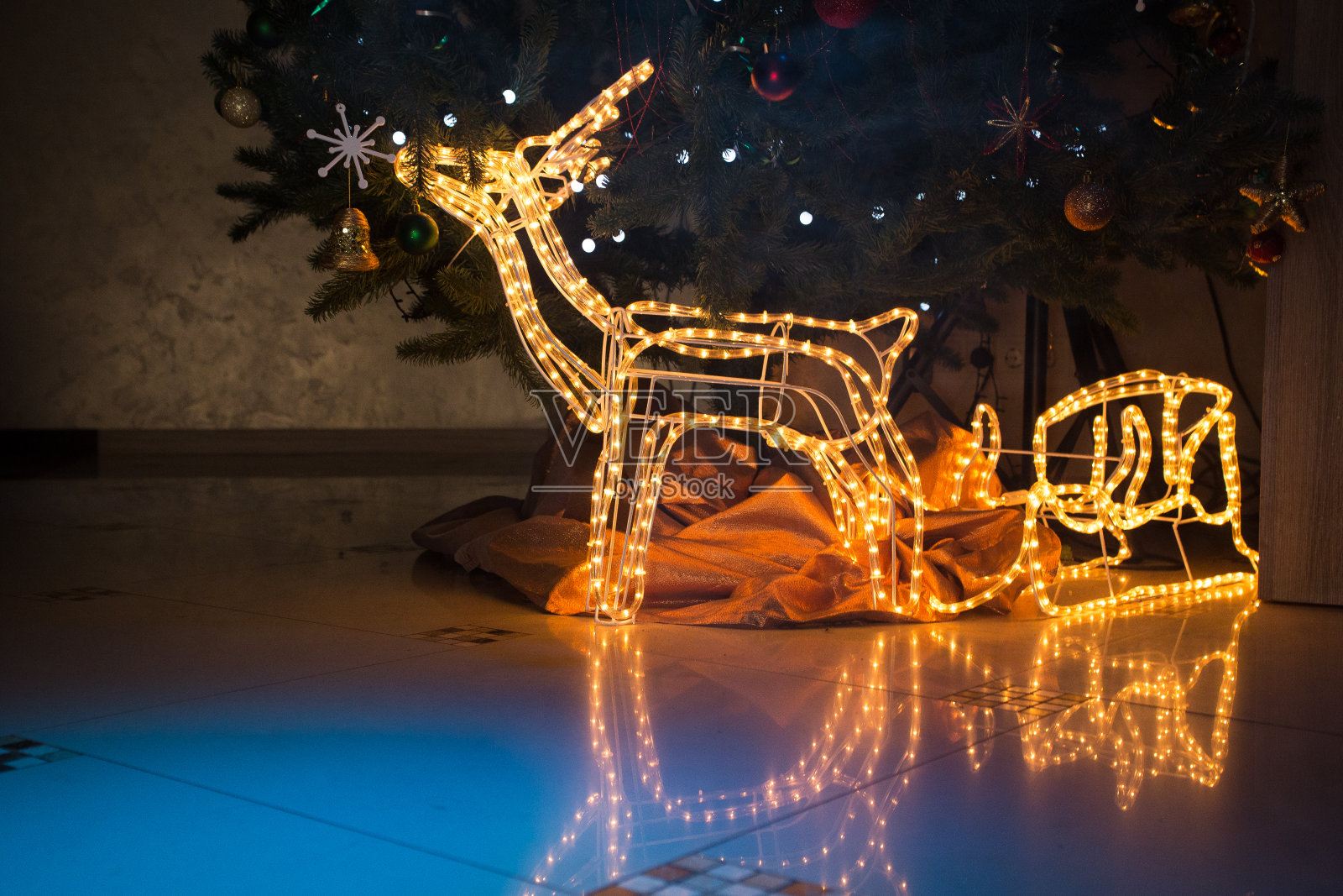 圣诞鹿站在圣诞树下。照片摄影图片