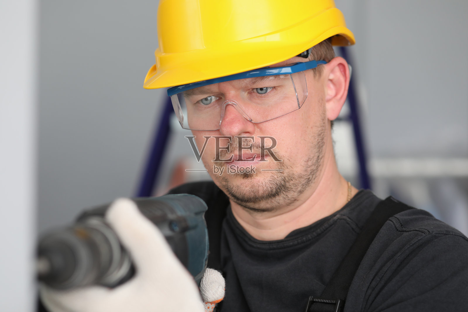 男成年工人戴黄盔，手持电钻。照片摄影图片