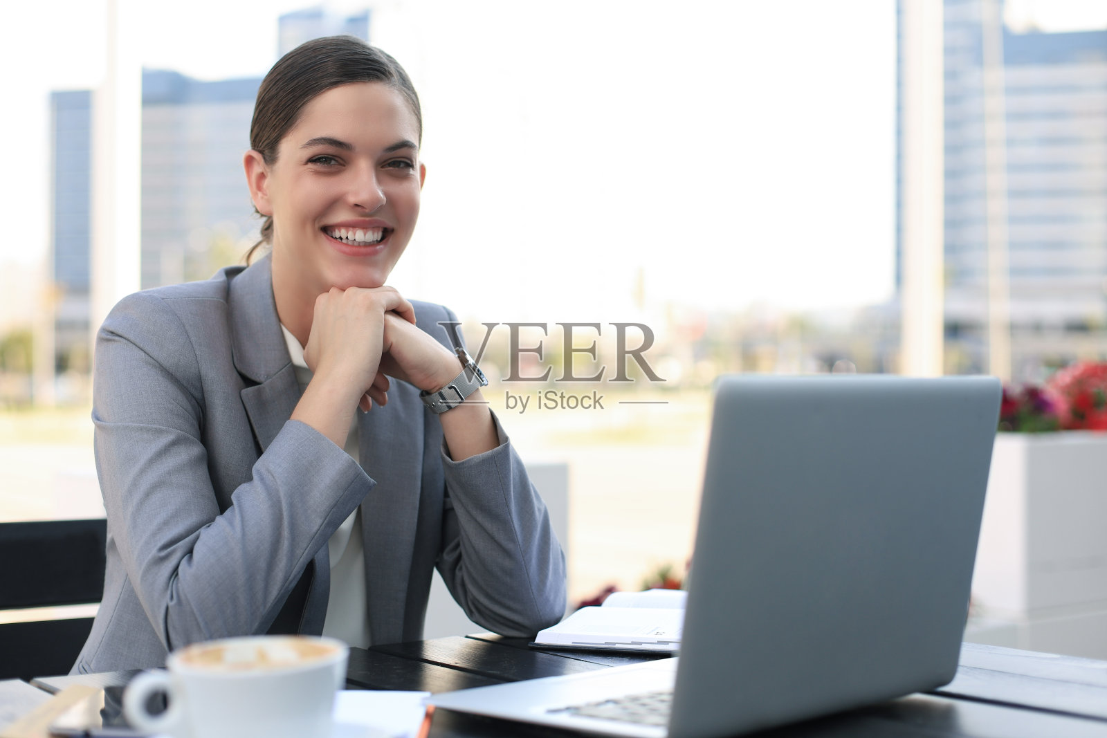 成功的商业女性使用笔记本电脑，微笑着坐在咖啡馆，户外。照片摄影图片