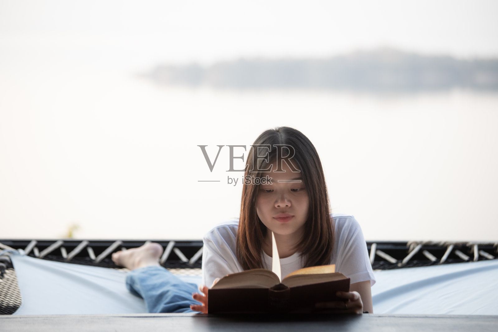 读一本书的亚洲女人。照片摄影图片