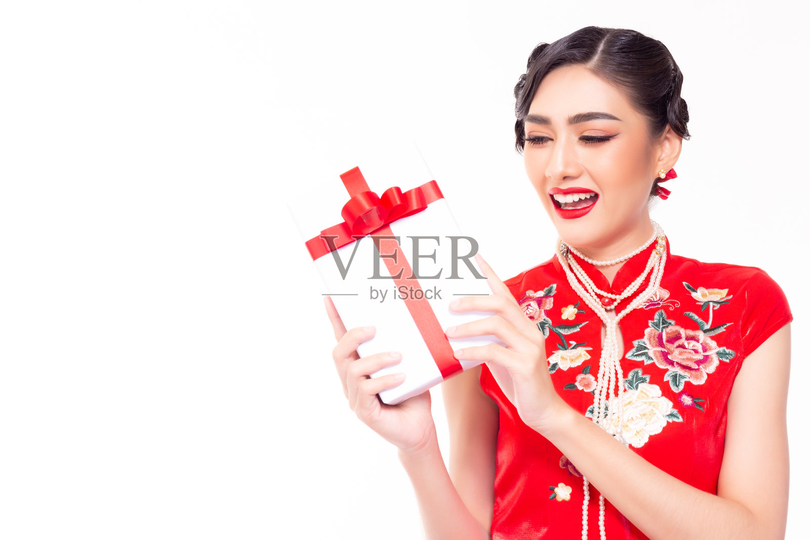 年轻美丽的亚洲女子在中国新年得到礼物。迷人美丽的女孩在收到礼物时得到幸福，笑脸盈满。她穿着漂亮的中式服装。她拿着礼盒。工作室白色照片摄影图片
