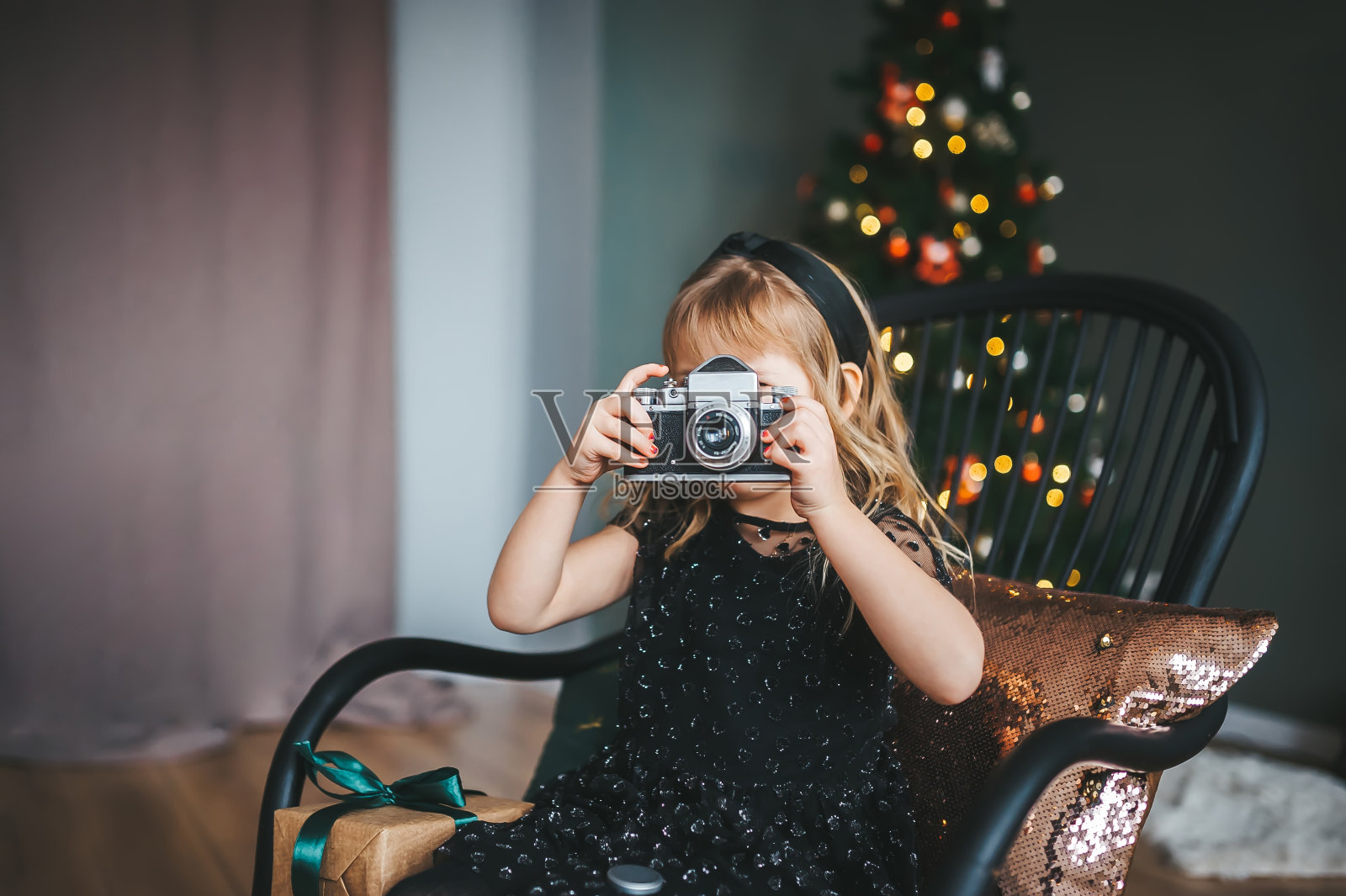 小女孩在圣诞树旁用老式相机拍照照片摄影图片
