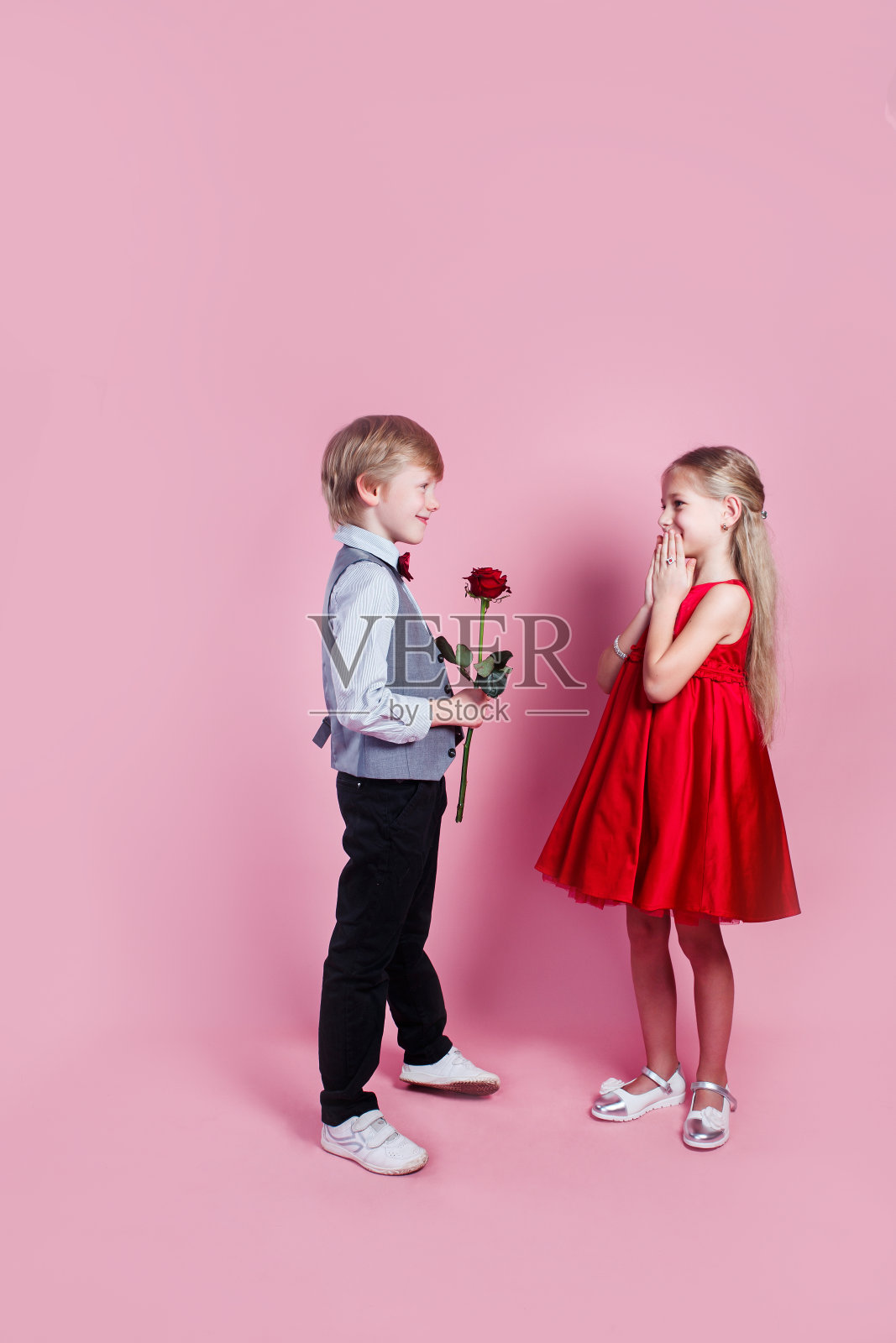 小男孩送给可爱的女孩红玫瑰，情人节照片摄影图片