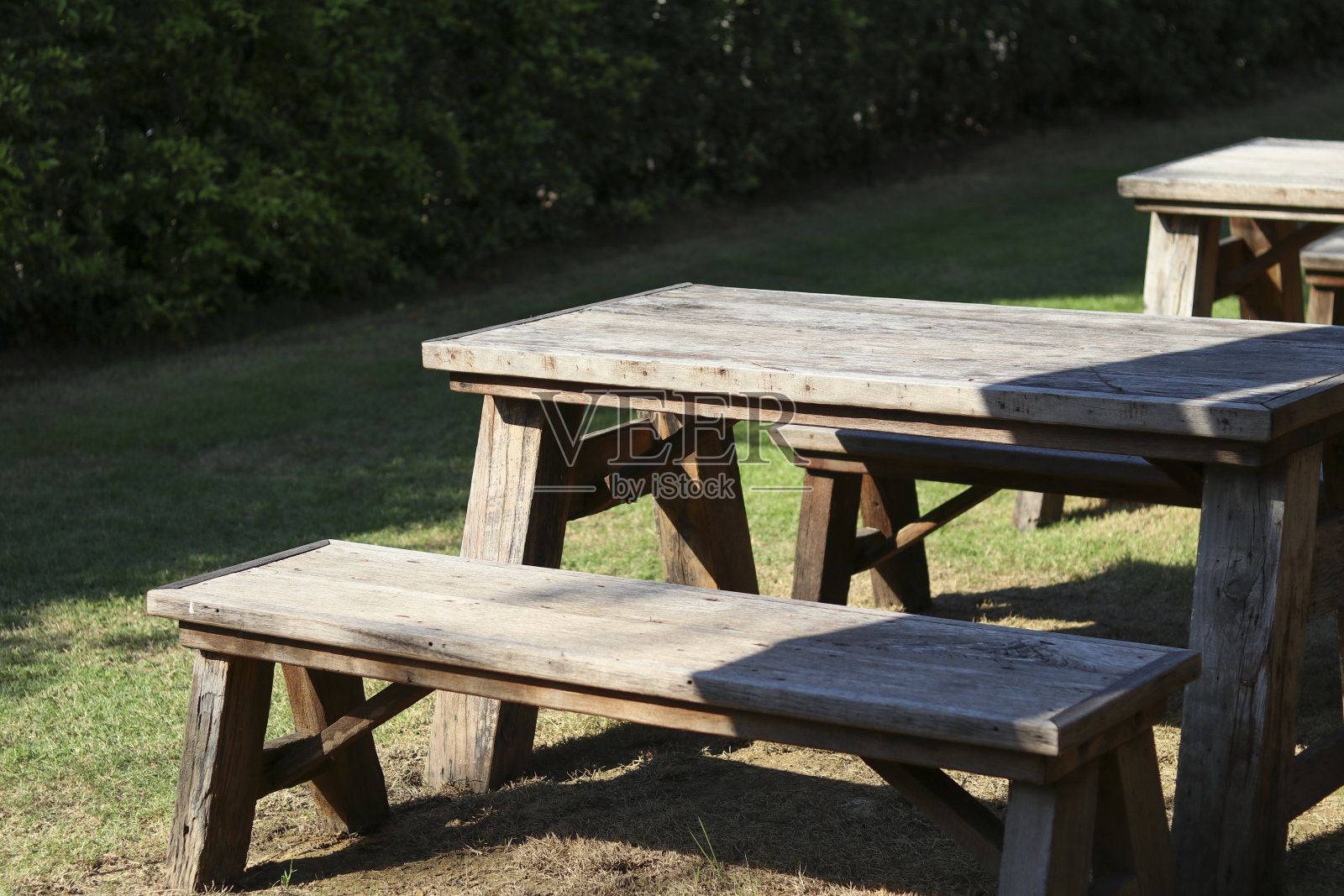 一张木桌放在花园里，阳光照在桌子上。照片摄影图片