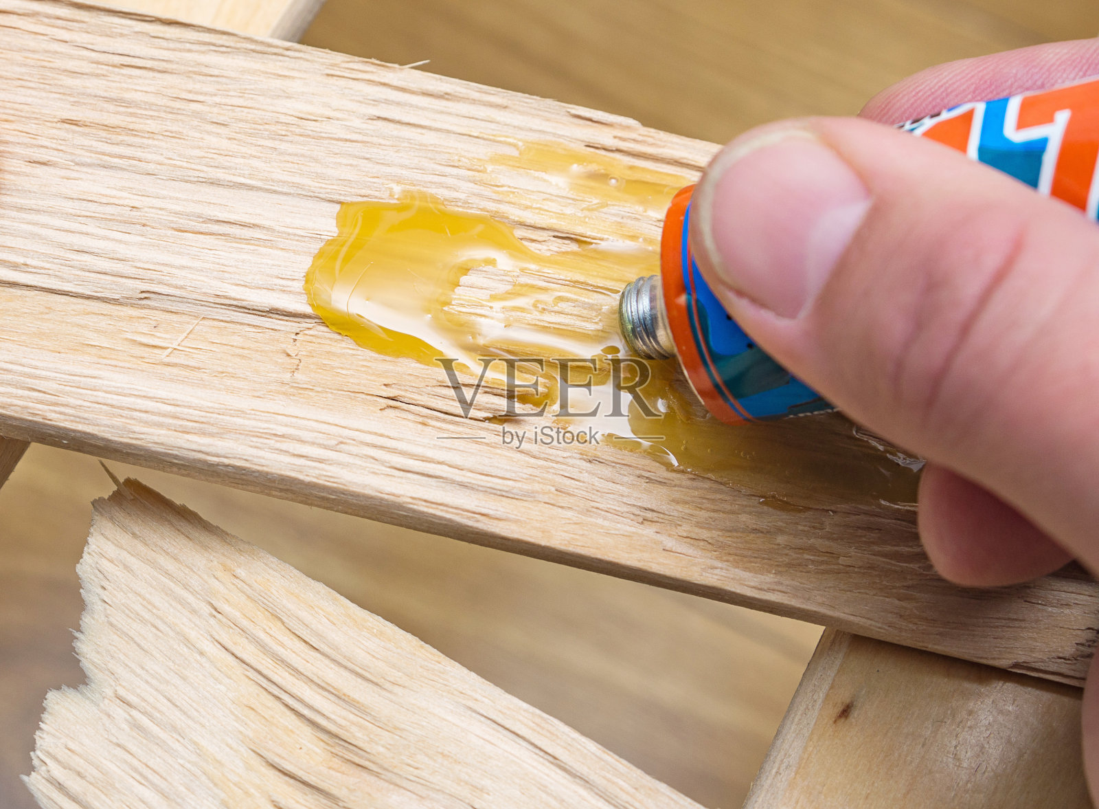 在家修理家具。木匠把胶水涂在有裂缝的木板上。特写,有选择性的重点。照片摄影图片