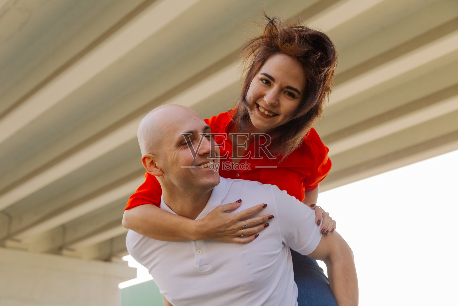 桥上一个男人后面的快乐女孩。情侣玩得开心照片摄影图片