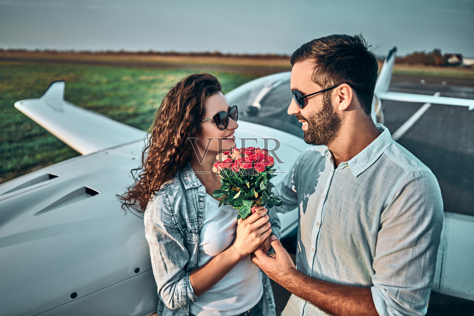 微笑的男人正在看漂亮的女士花在私人飞机上的背景照片摄影图片