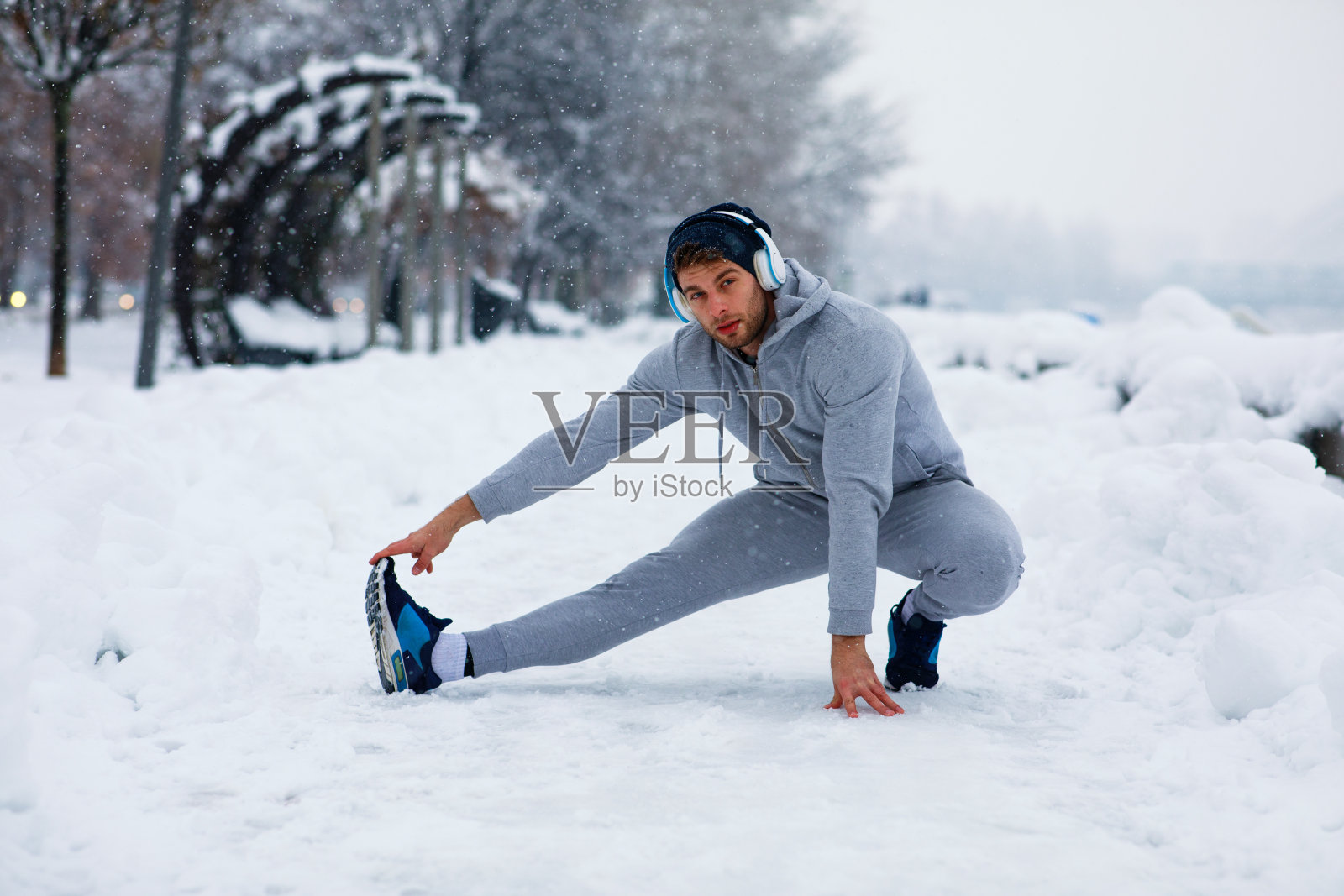 一个年轻人在下雪天在城市里伸伸腿照片摄影图片