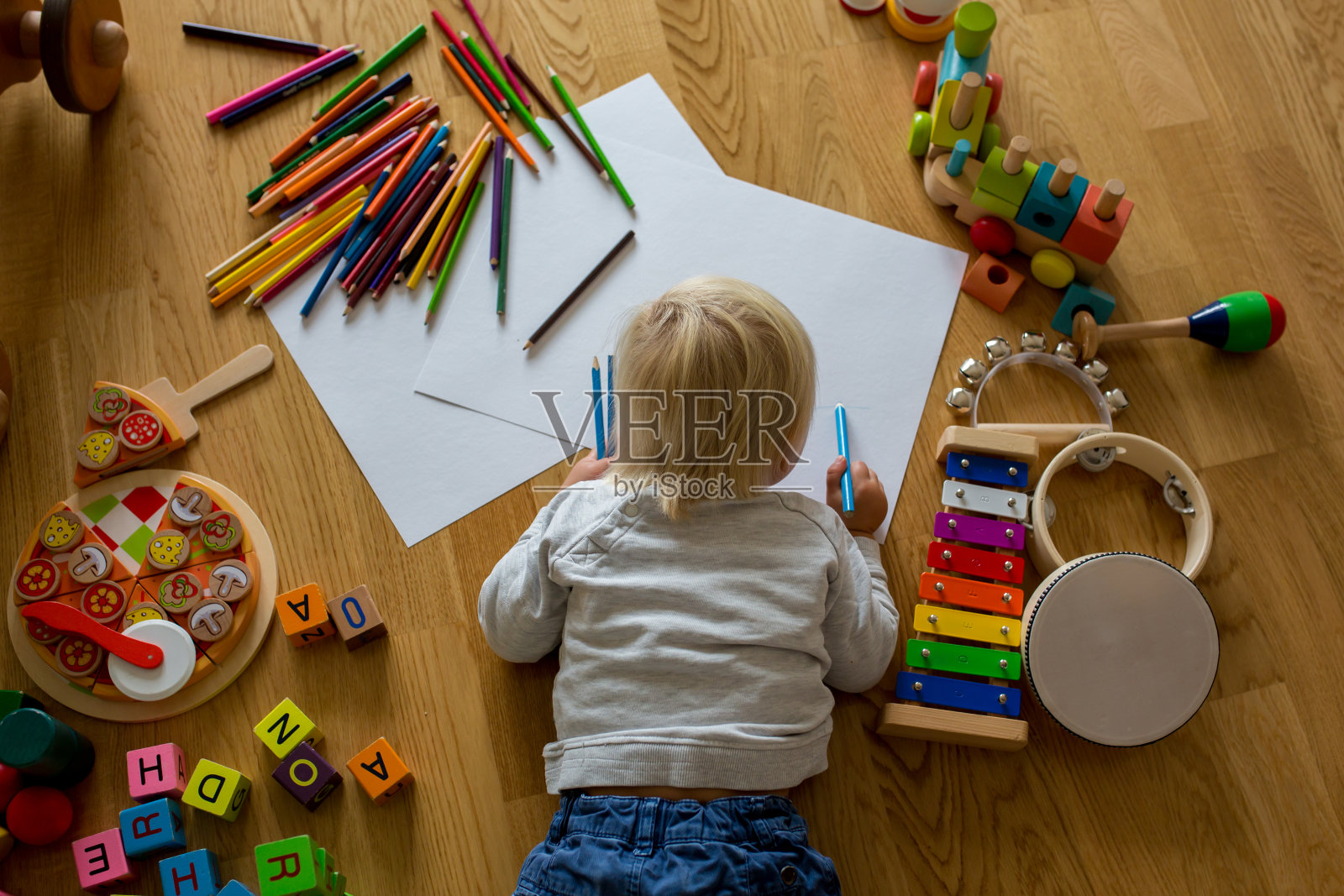 金发的小男孩，用彩色蜡笔和彩色笔画画，玩着木制玩具照片摄影图片