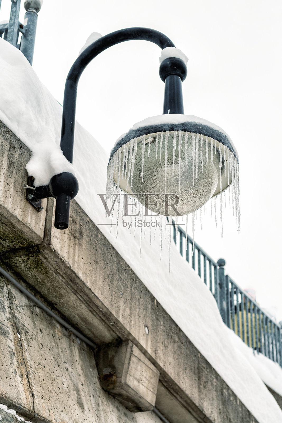 寒冷的冬天，室外街灯挂在挂满冰柱的混凝土墙上。冬季天气季节背景照片摄影图片